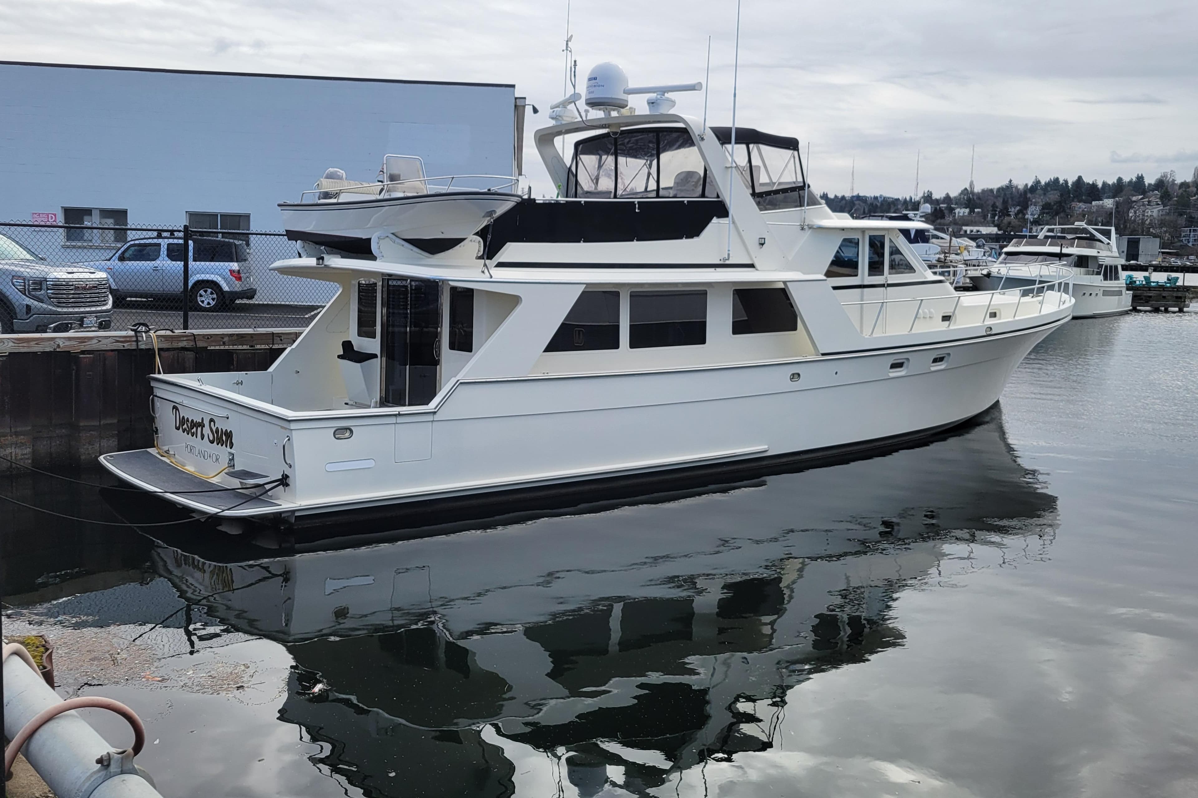 1998 Tollycraft 65 Pilothouse yacht docked in a marina, reflecting on calm water.