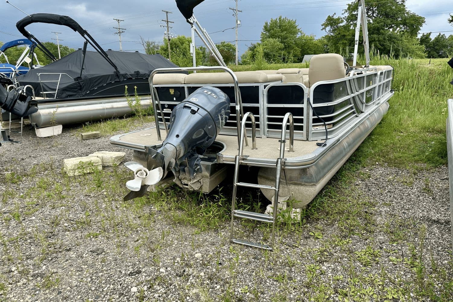 2015 South Bay 524 CR pontoon boat with outboard motor, parked on gravel.