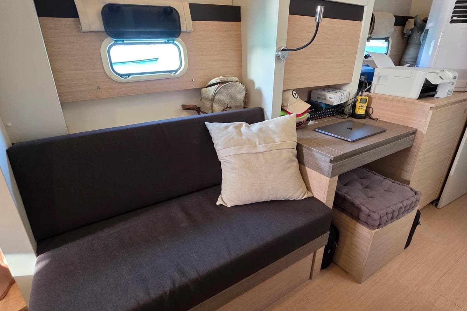 Cozy interior of 2016 Bali 4.5 yacht with sofa, desk, and window.