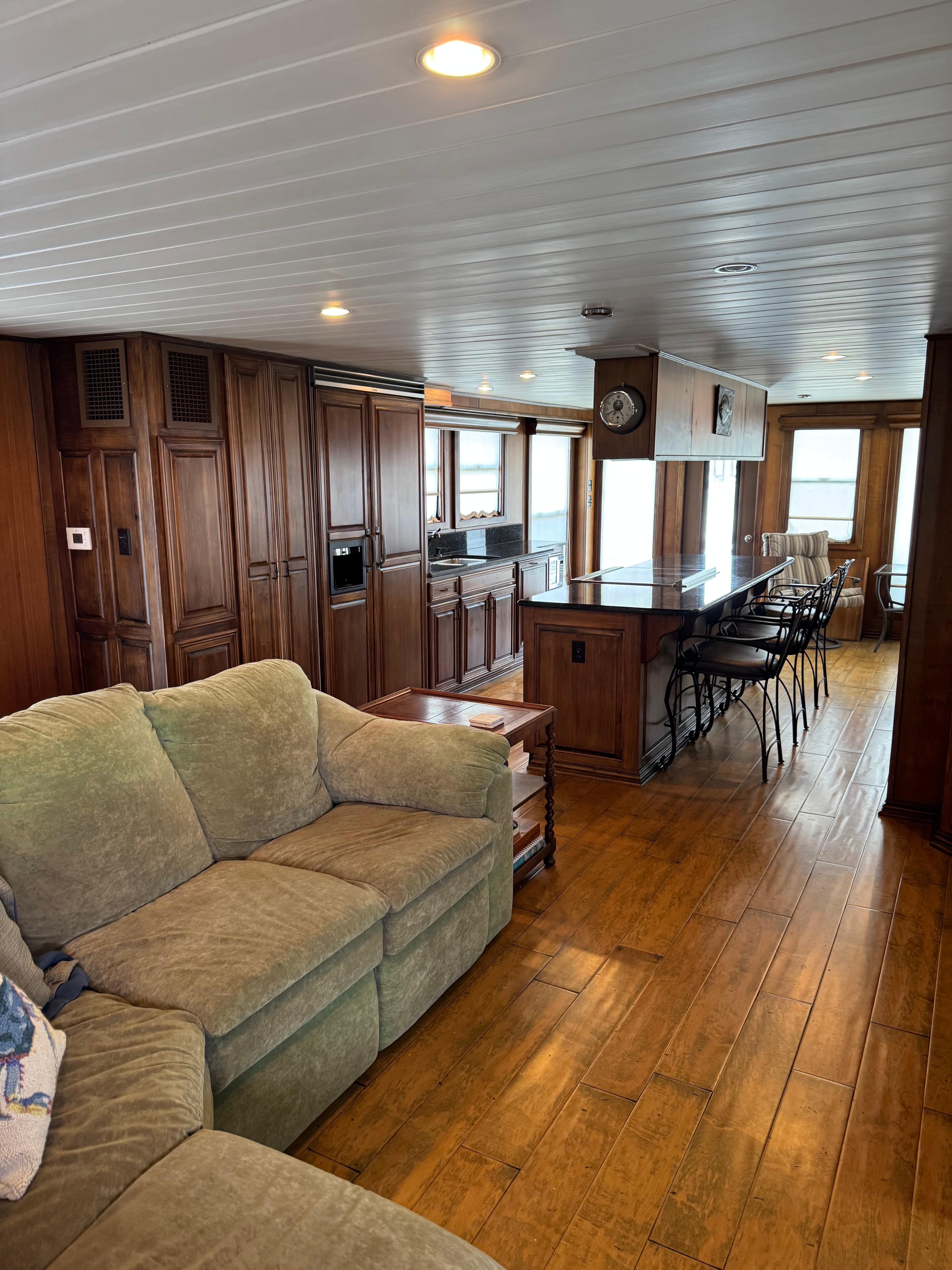 Luxurious 2003 custom houseboat interior with wooden flooring, cozy seating, and modern kitchen.