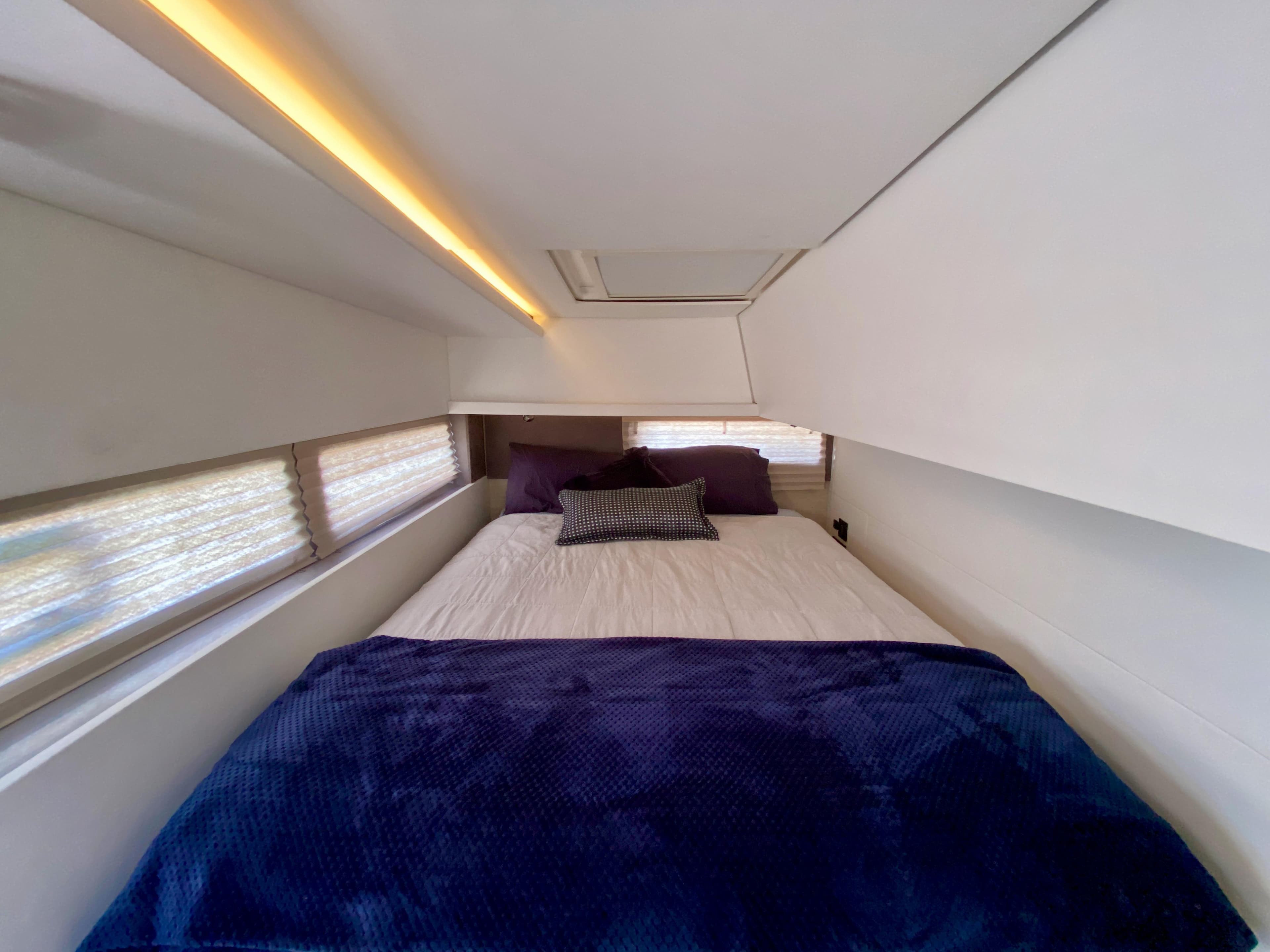 Cozy bedroom in 2021 Leopard 45 yacht with modern lighting and plush bedding.