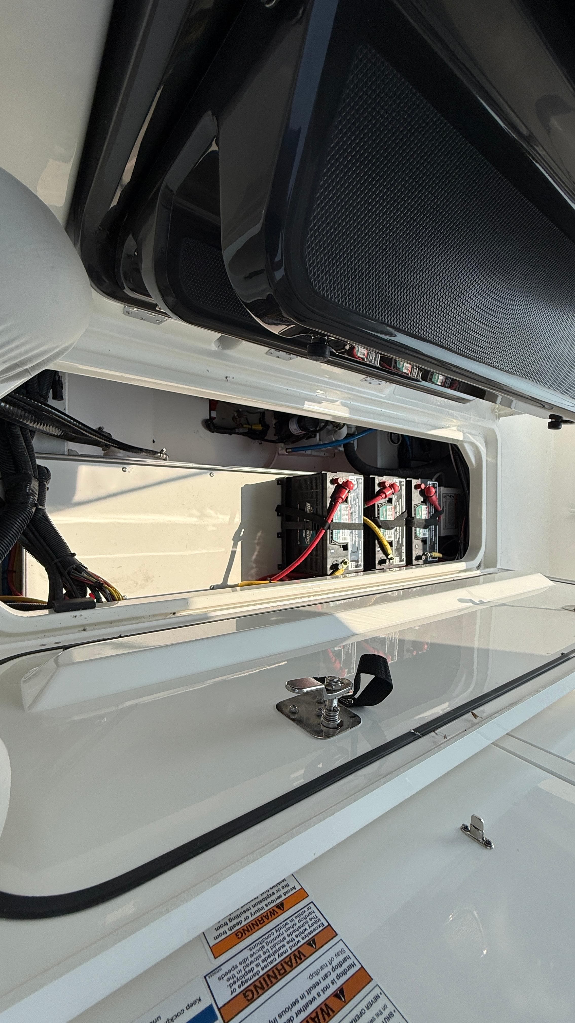 2025 Pursuit S 328 Sport boat battery compartment with wiring and secure latch.
