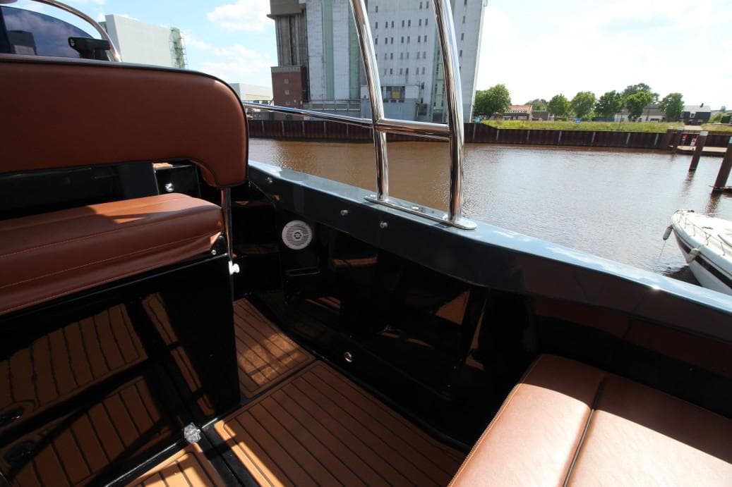 Luxurious boat interior with brown leather seats, wooden flooring, and waterfront view. Custom Tecnoteam 4k7, 2024.