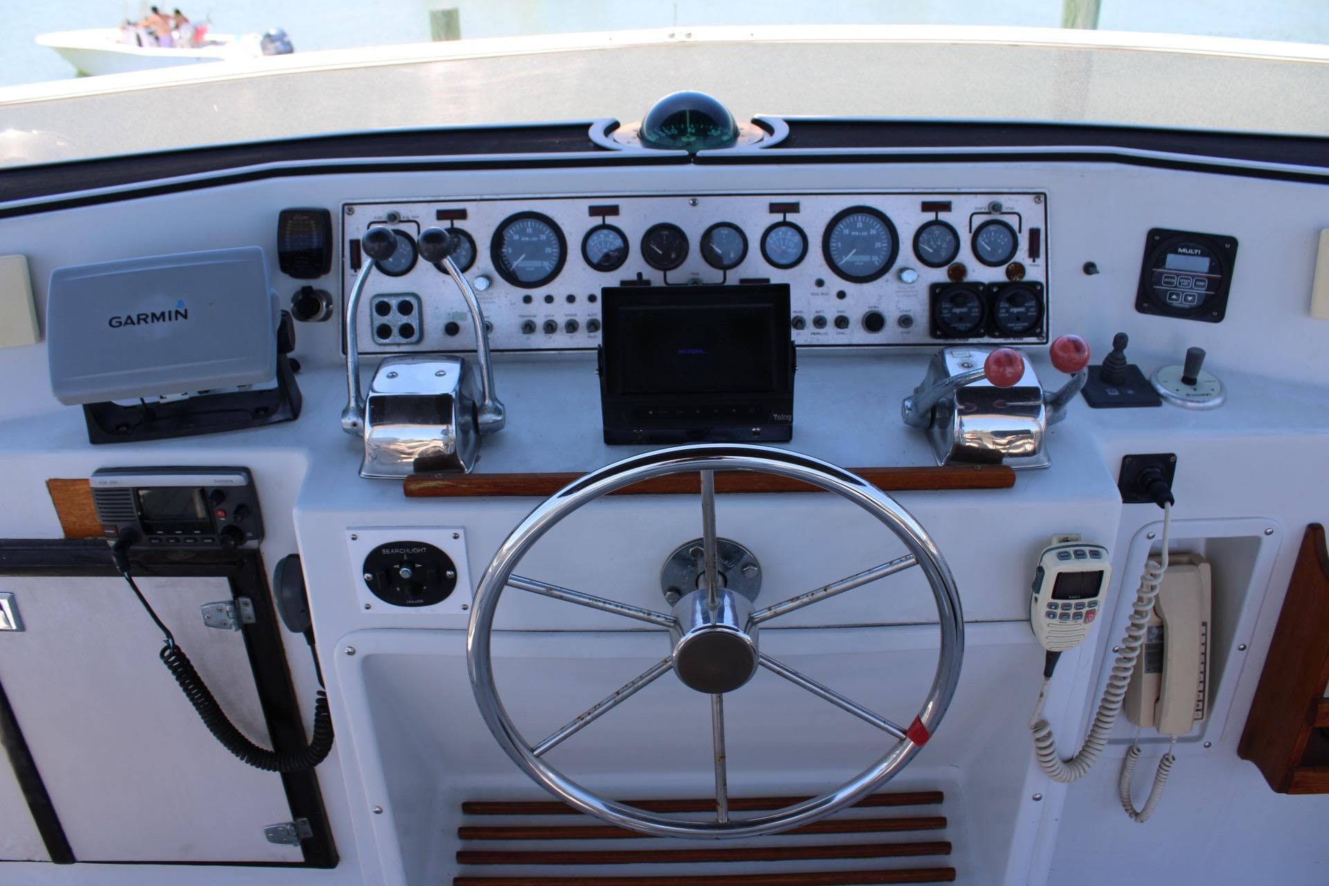 Helm of 1988 Chris Craft Constellation with Garmin navigation and classic controls.