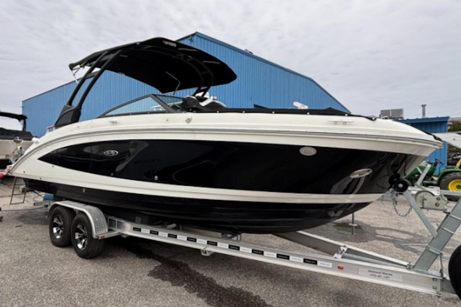 2021 Sea Ray SDX 270 boat on trailer, parked near a blue building.