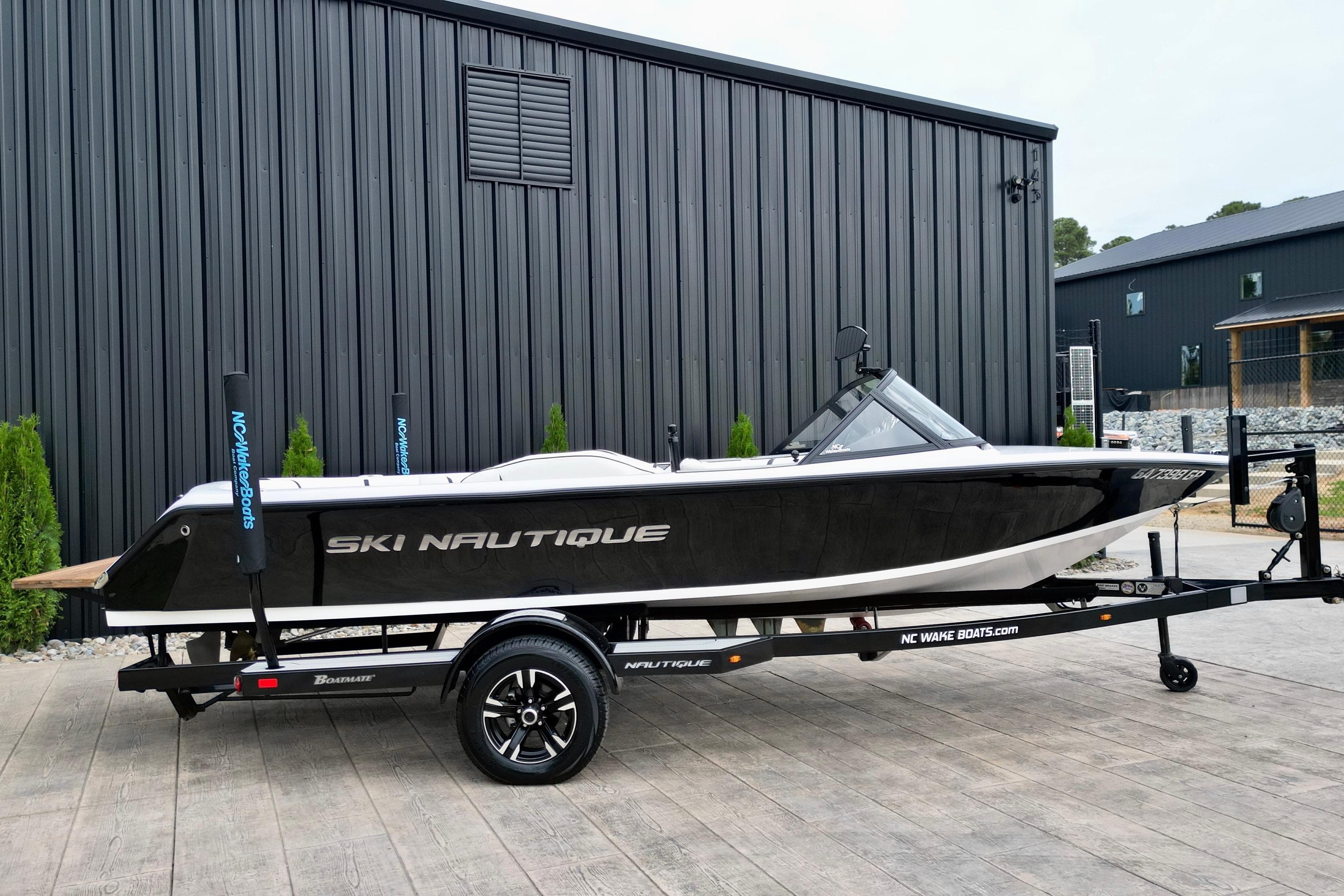 1994 Nautique Ski Nautique boat on trailer, parked outside a modern building.