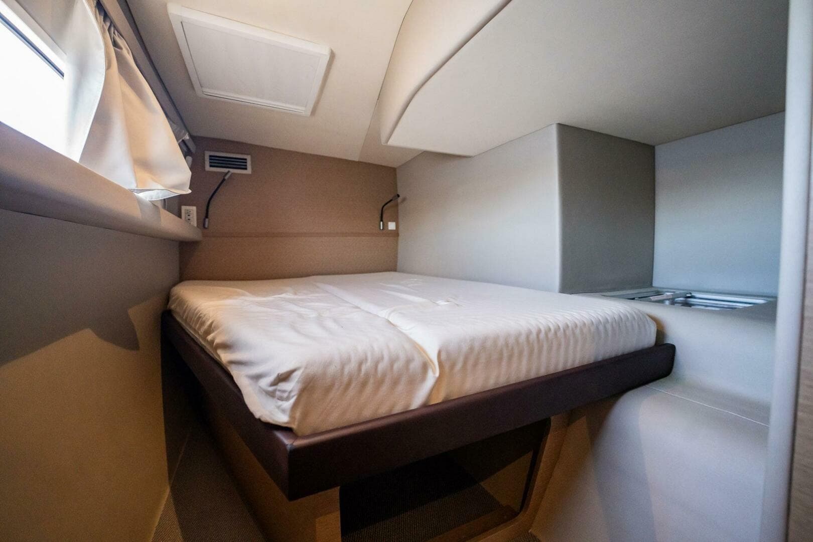 Cozy cabin interior of 2020 NEEL 51 trimaran with comfortable bed and window.