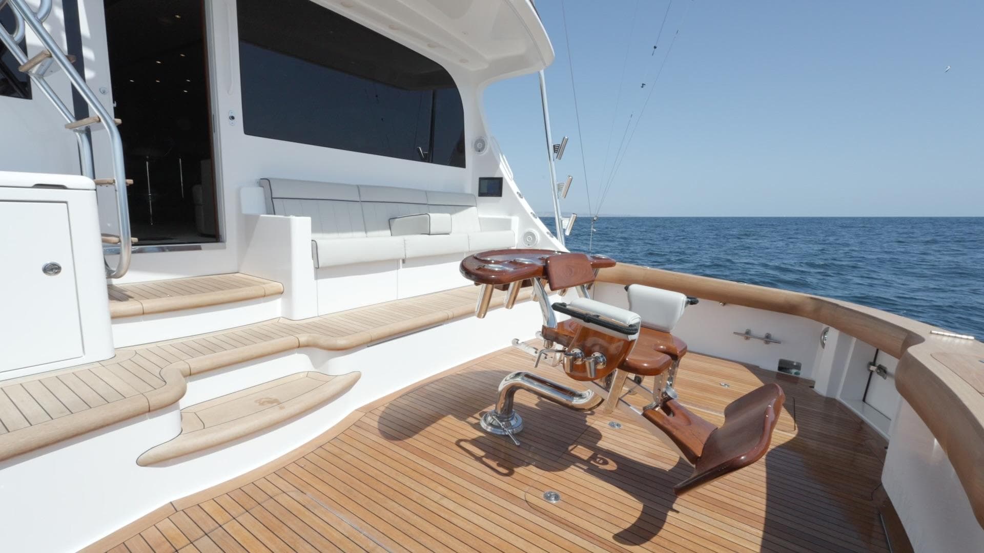 2018 Hatteras GT70 yacht deck with fishing chair, ocean view, and wooden flooring.