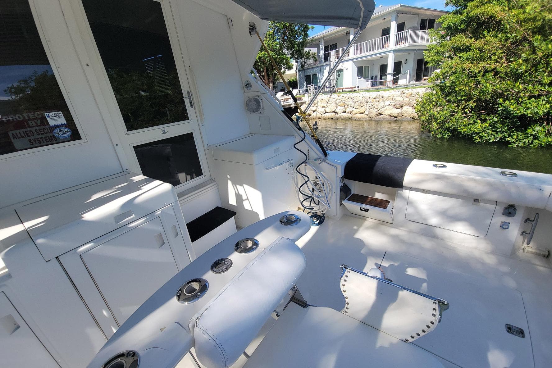 1989 Bertram 50 Convertible boat deck with fishing rod holders and seating, near waterfront homes.