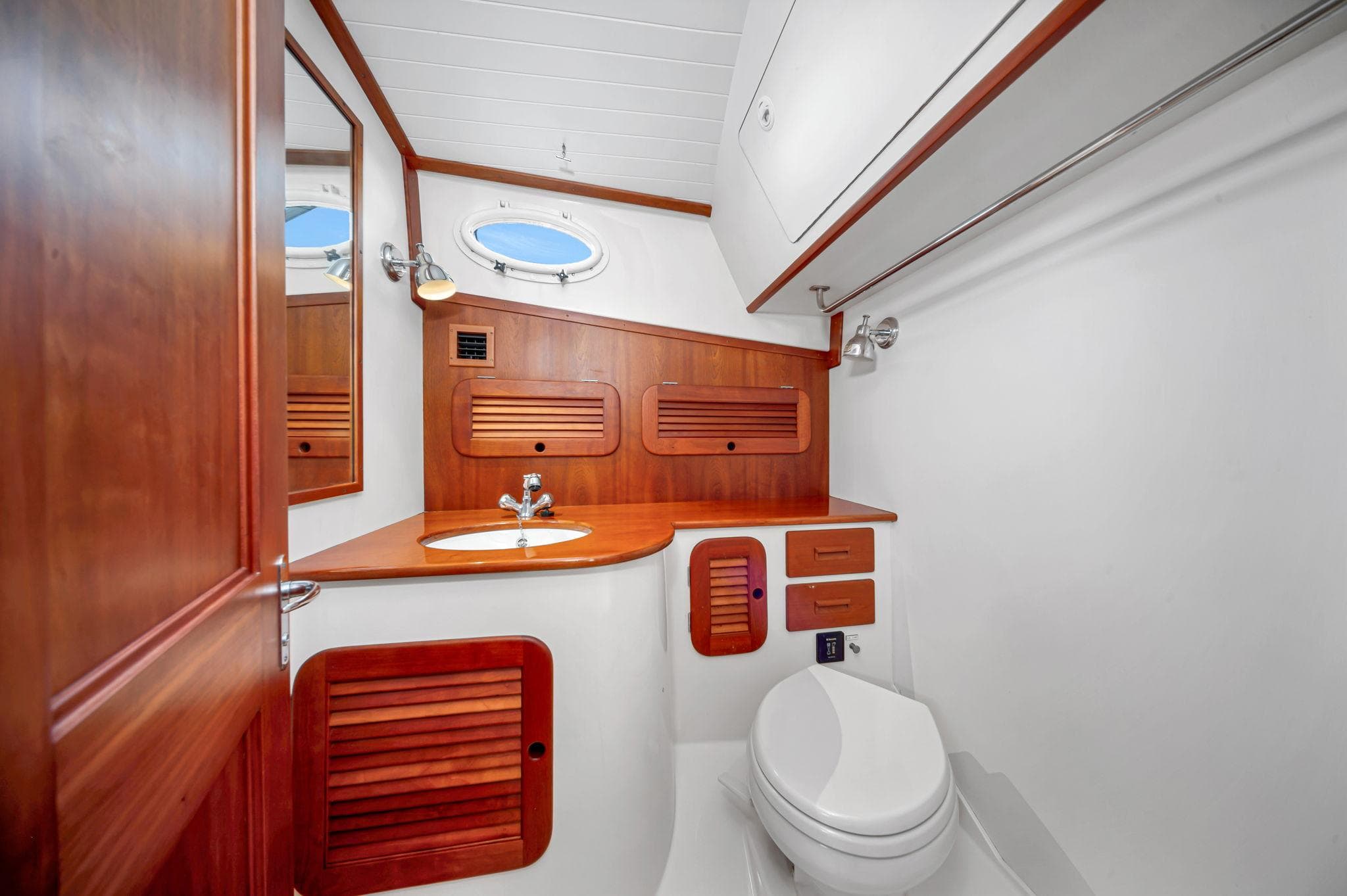 2014 Hinckley Picnic Boat 37 MKIII bathroom with wooden cabinetry and porthole window.