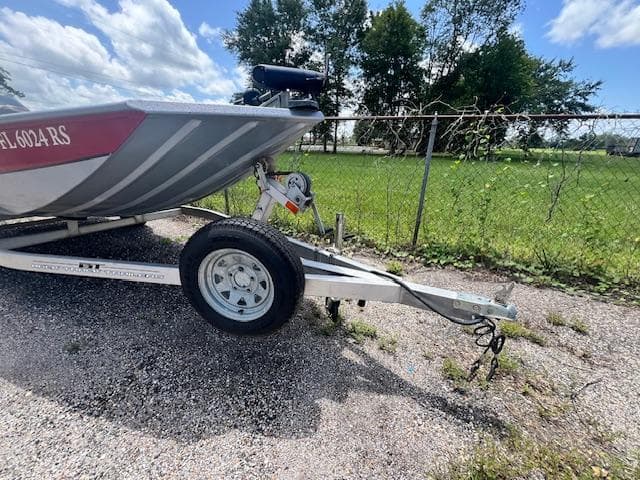 2017 Express XP7 boat on trailer, parked on gravel near chain-link fence.