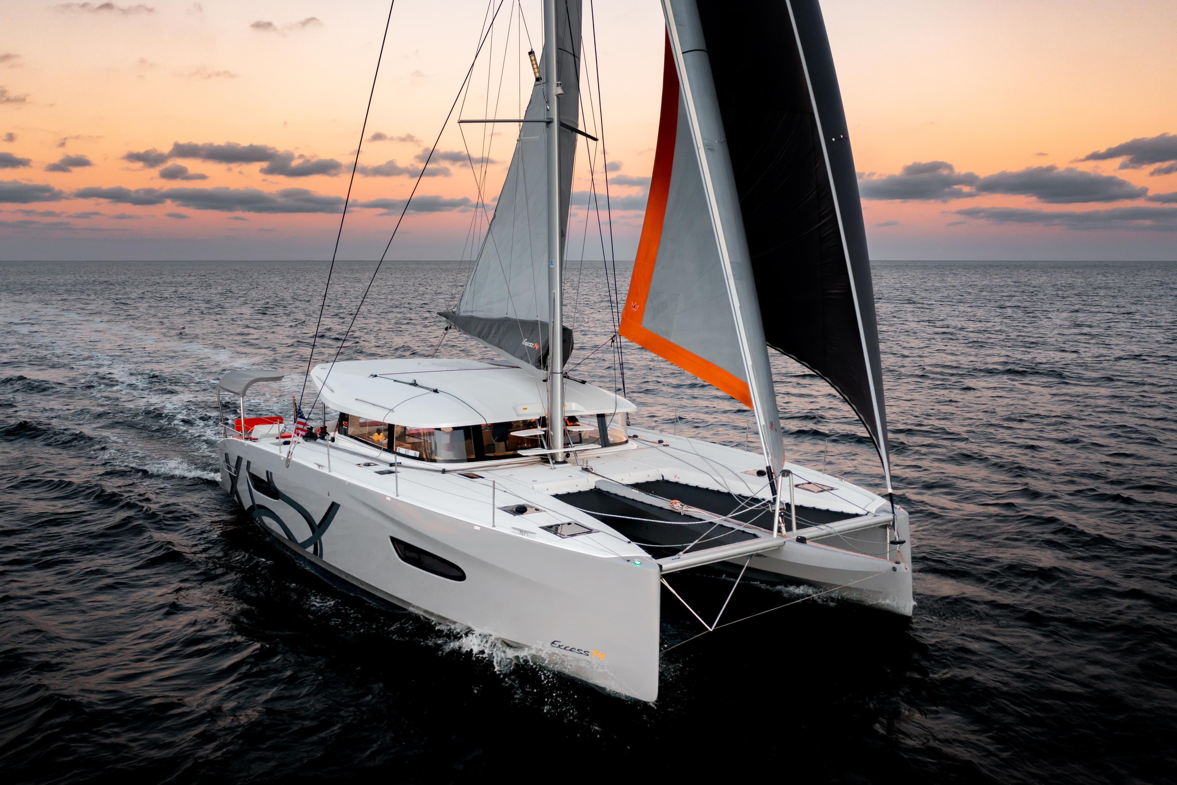 Sailing catamaran Excess 14, 2026 model, cruising at sunset on open sea.