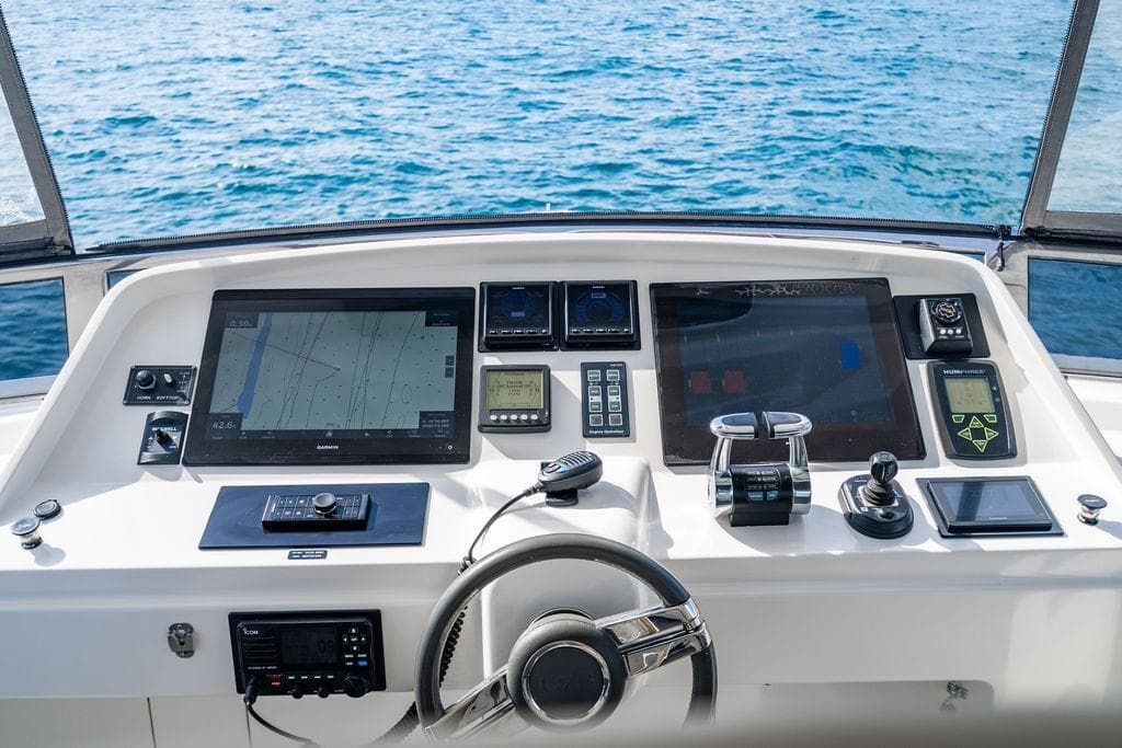 Control panel of a 2013 Lanzarote Ventuno 73 yacht with navigation screens and steering wheel.