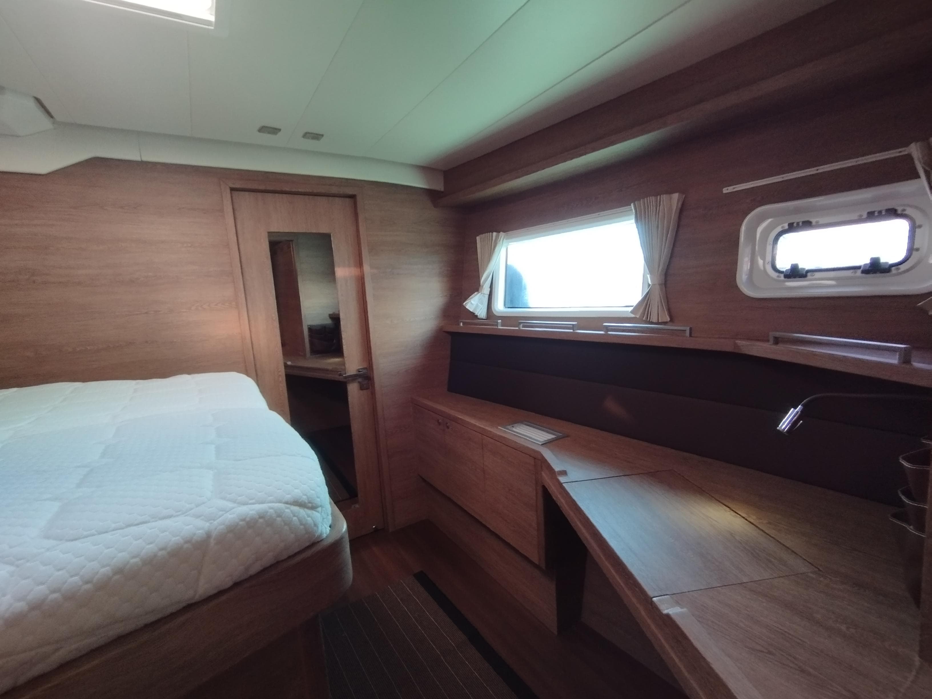Luxurious interior of 2012 Lagoon 620 yacht cabin with wooden furnishings and natural light.