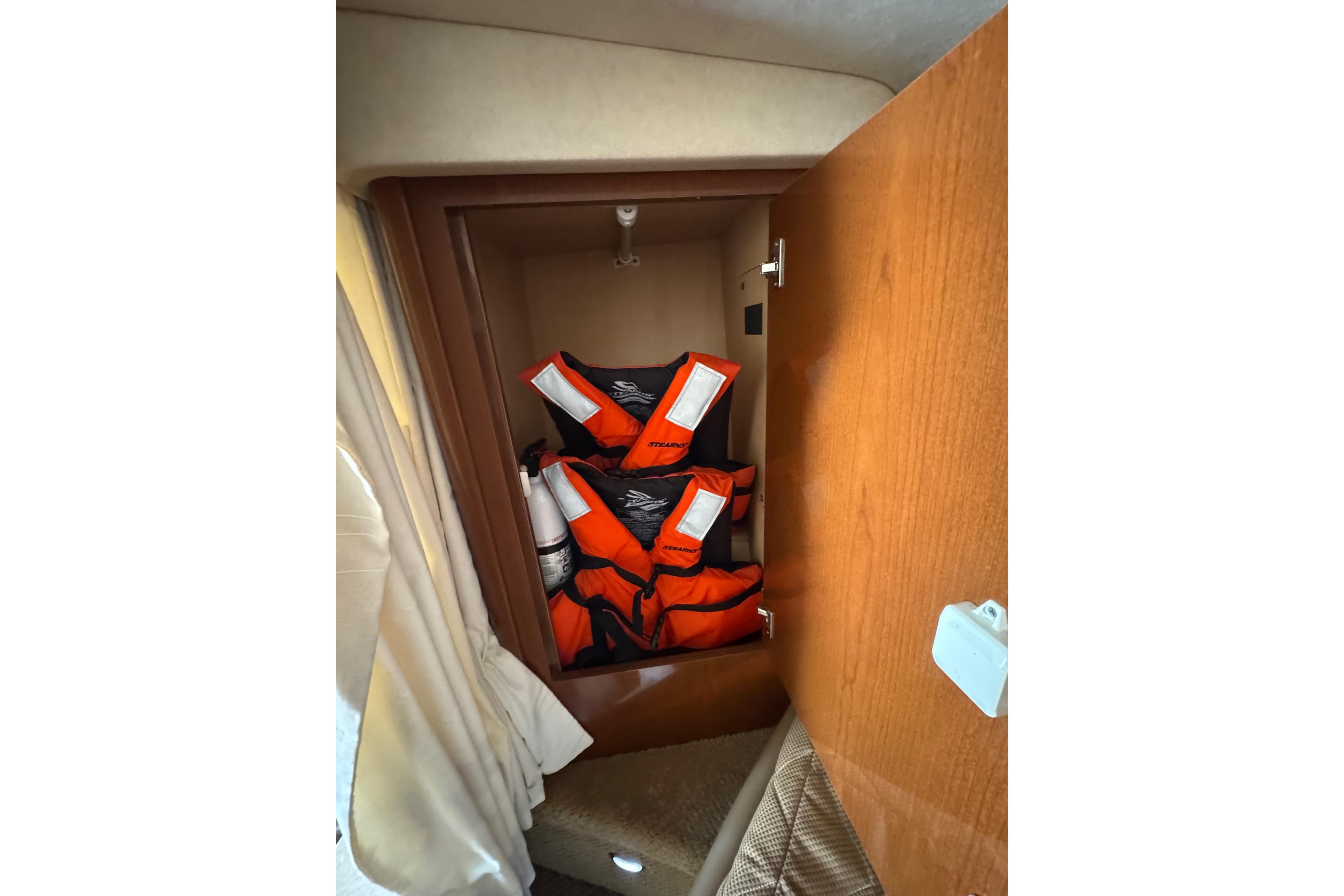 Life jackets stored in a wooden cabinet on a 2010 Searay 330 Sundancer boat.