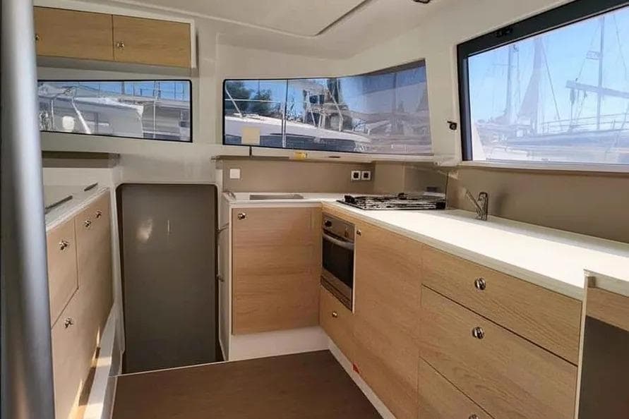 Modern kitchen interior of 2019 Bali 4.3 catamaran with wood cabinetry and large windows.