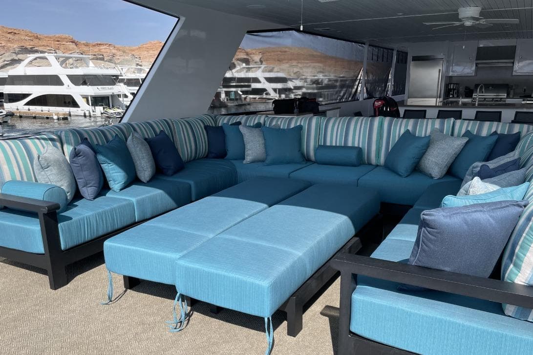 Luxurious yacht interior with blue cushioned seating, striped pillows, and marina view.