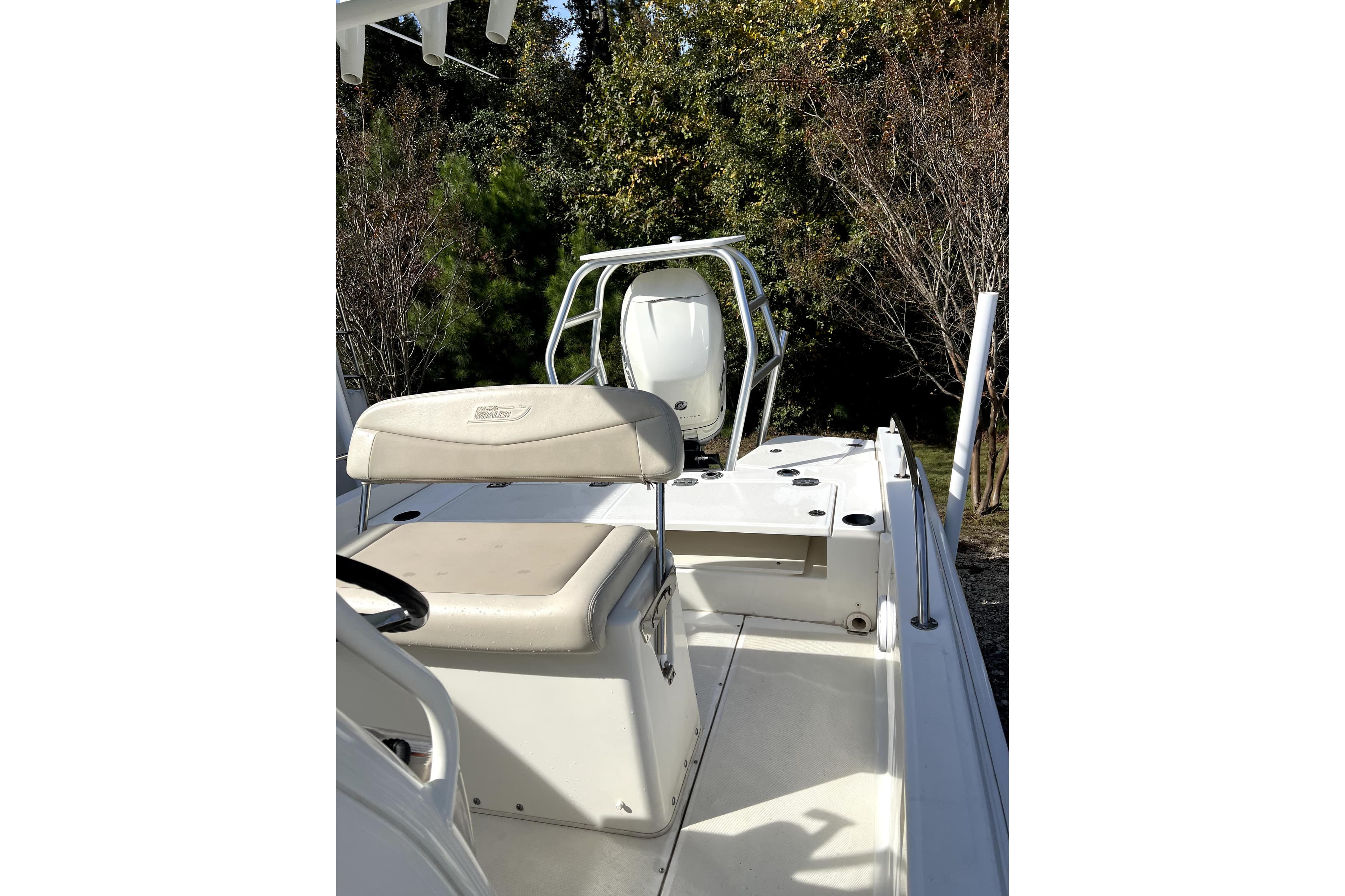 2018 Boston Whaler 240 Dauntless boat interior with seating and console, surrounded by trees.