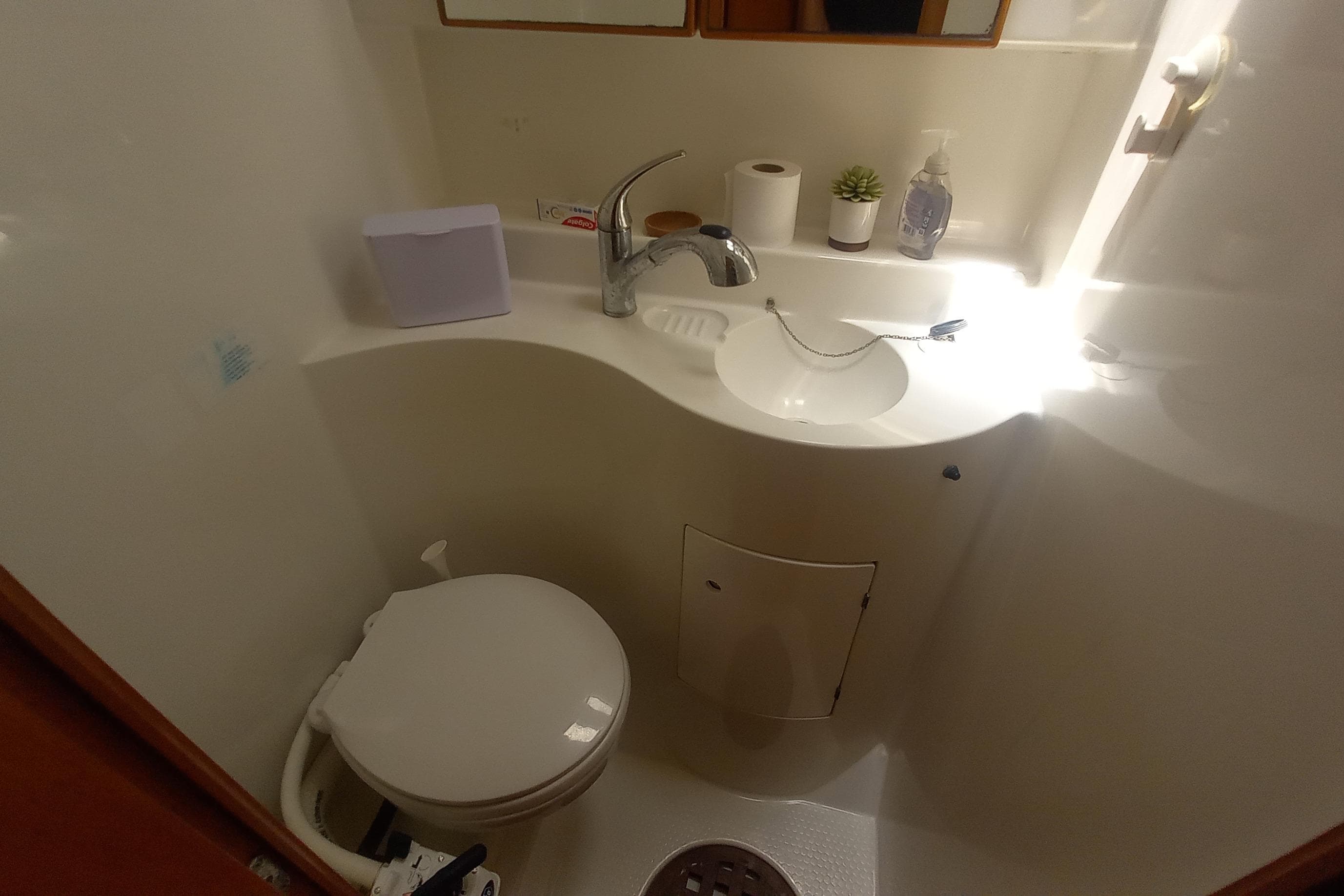 Compact bathroom in a 2002 Lagoon 470 yacht, featuring a toilet, sink, and toiletries.