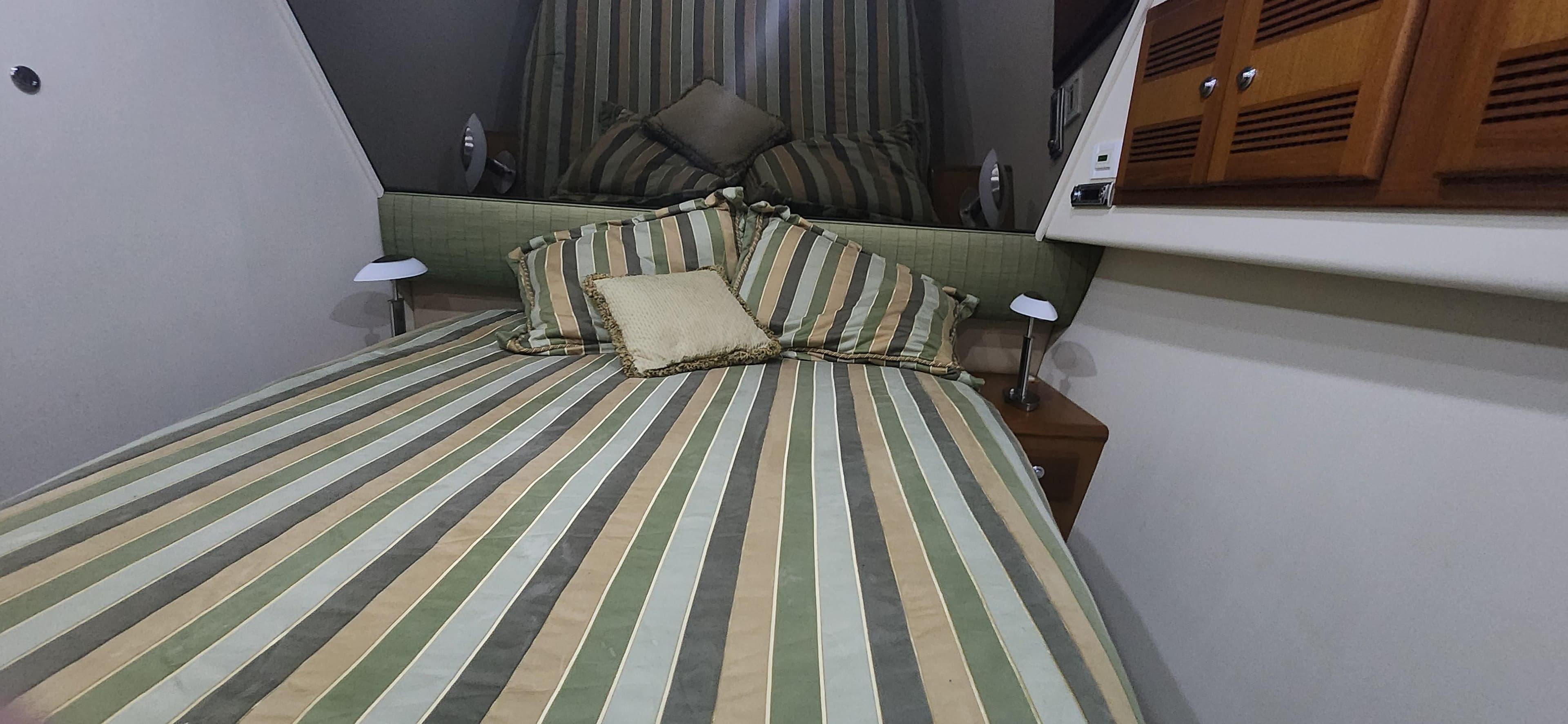 2004 Cabo 48 Convertible cabin with striped bedding and wooden cabinets.
