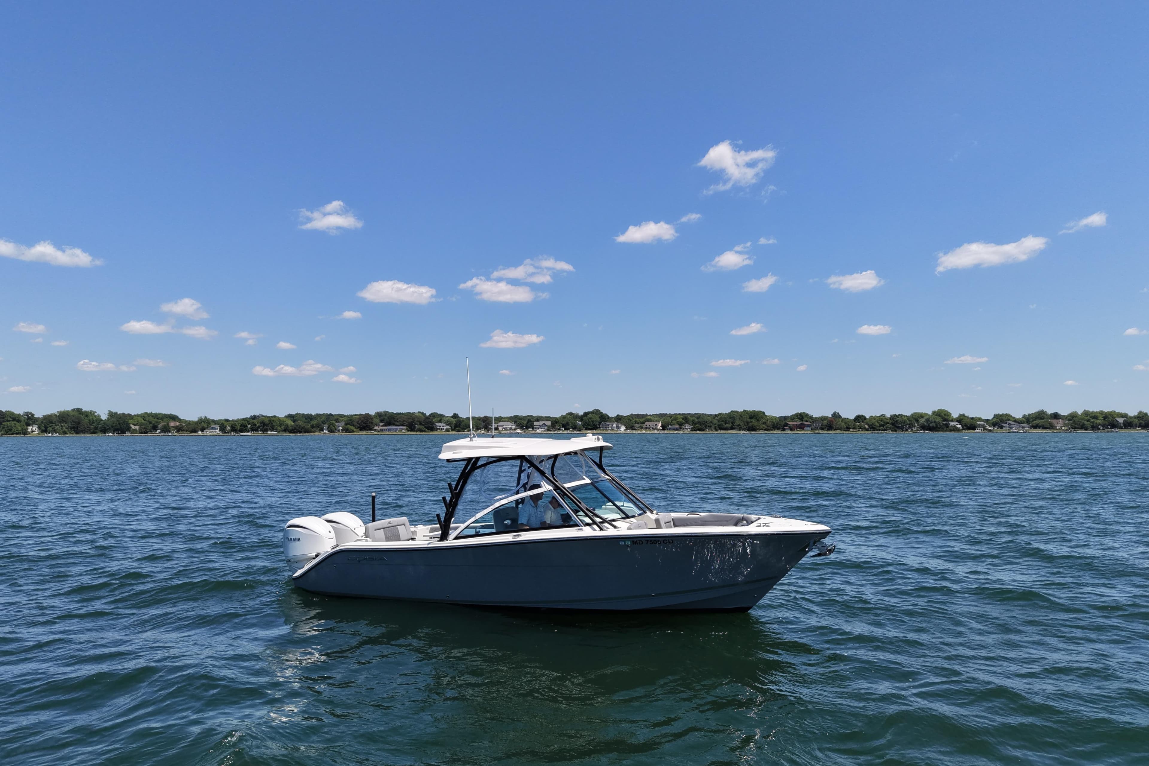 2024 Cobia 280 Dual Console boat on a sunny lake with clear skies.