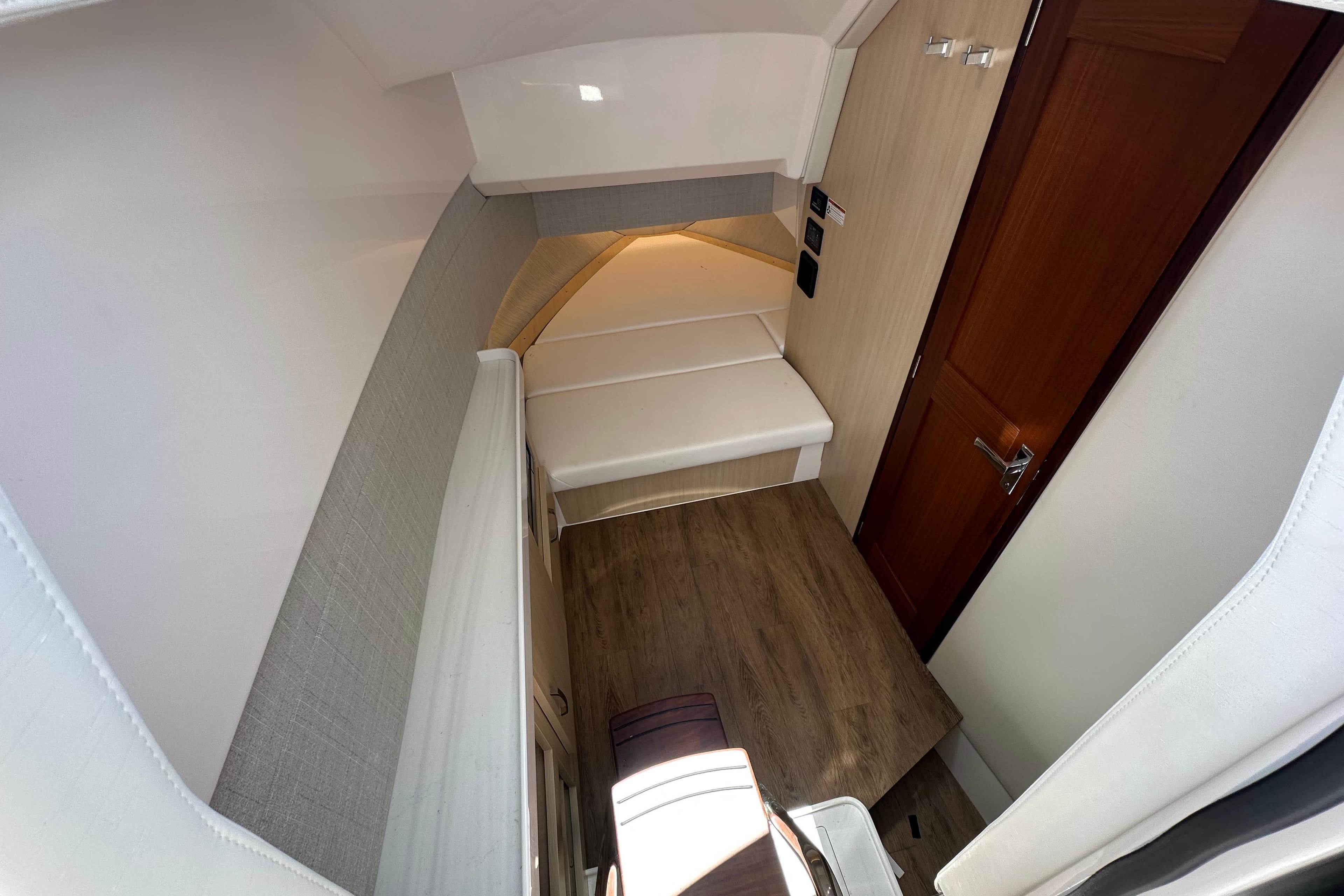 Interior cabin of 2025 Regal 38 SAV boat with wood flooring and cozy seating.