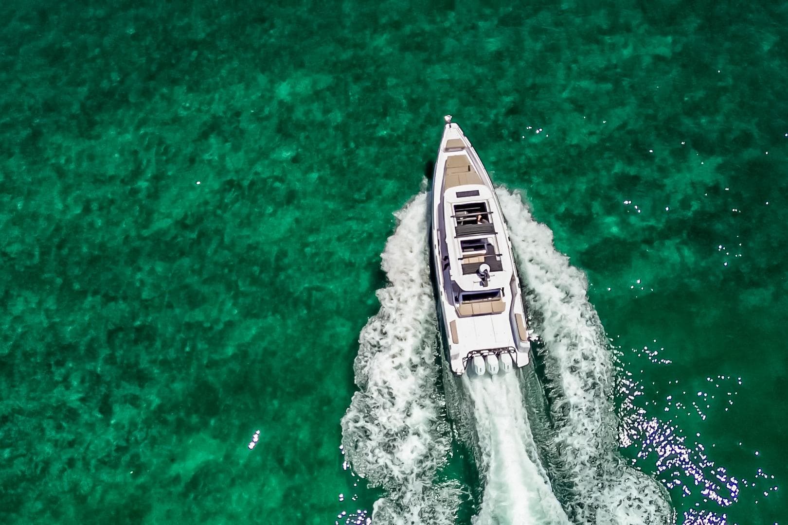 2026 Axopar 45 Cross Top cruising on clear turquoise waters, aerial view.