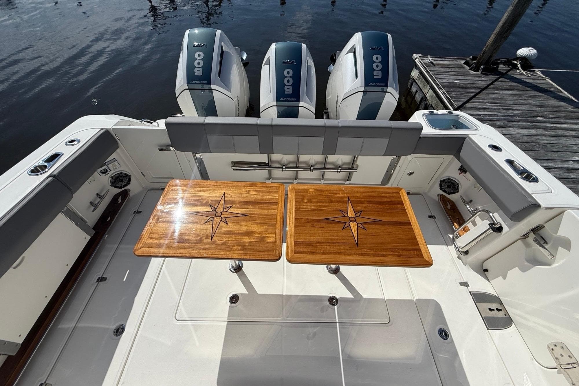 2024 Boston Whaler 420 Outrage boat deck with wooden tables and triple outboard engines.