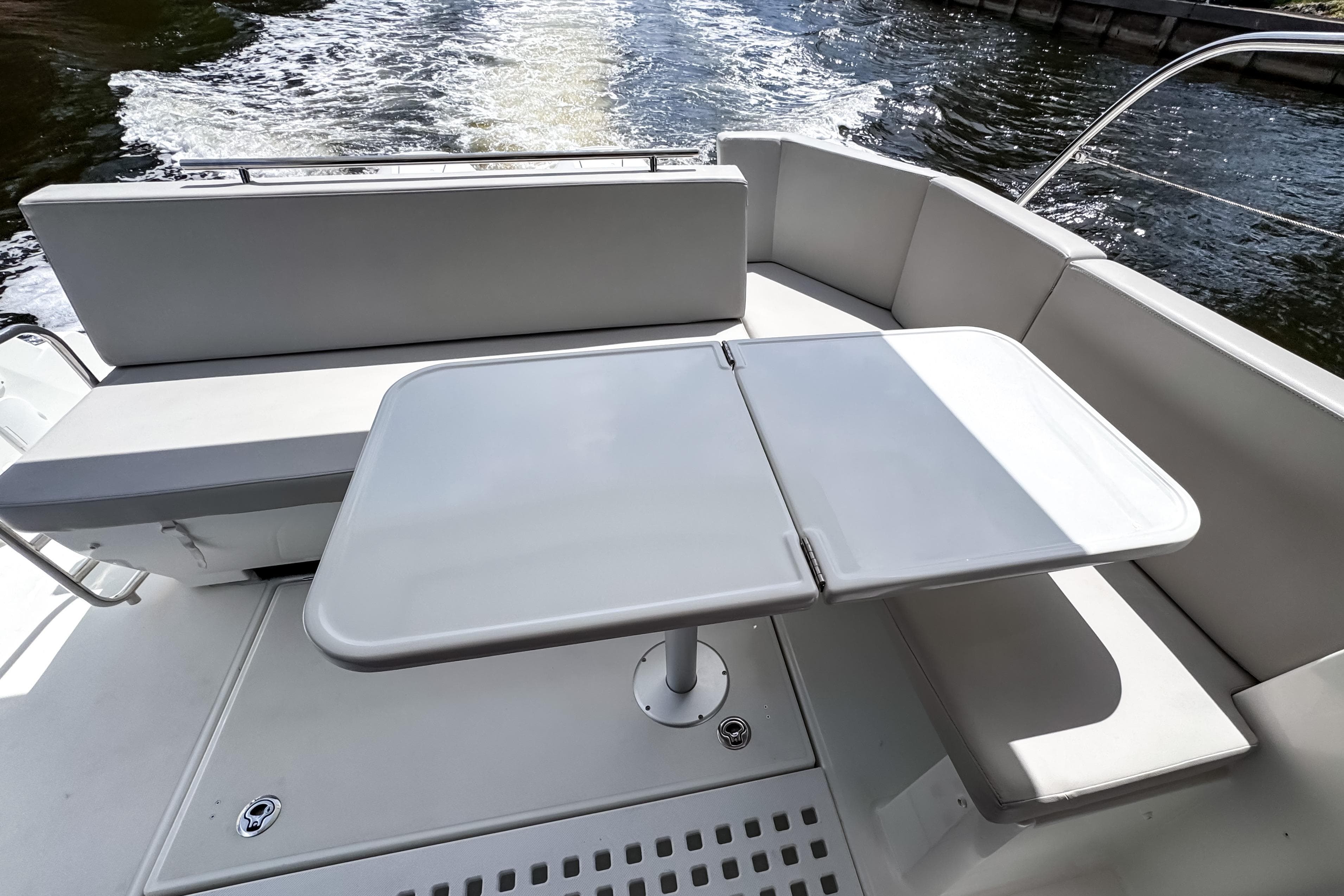 2023 Beneteau Antares 11 boat deck with seating and table, cruising on water.