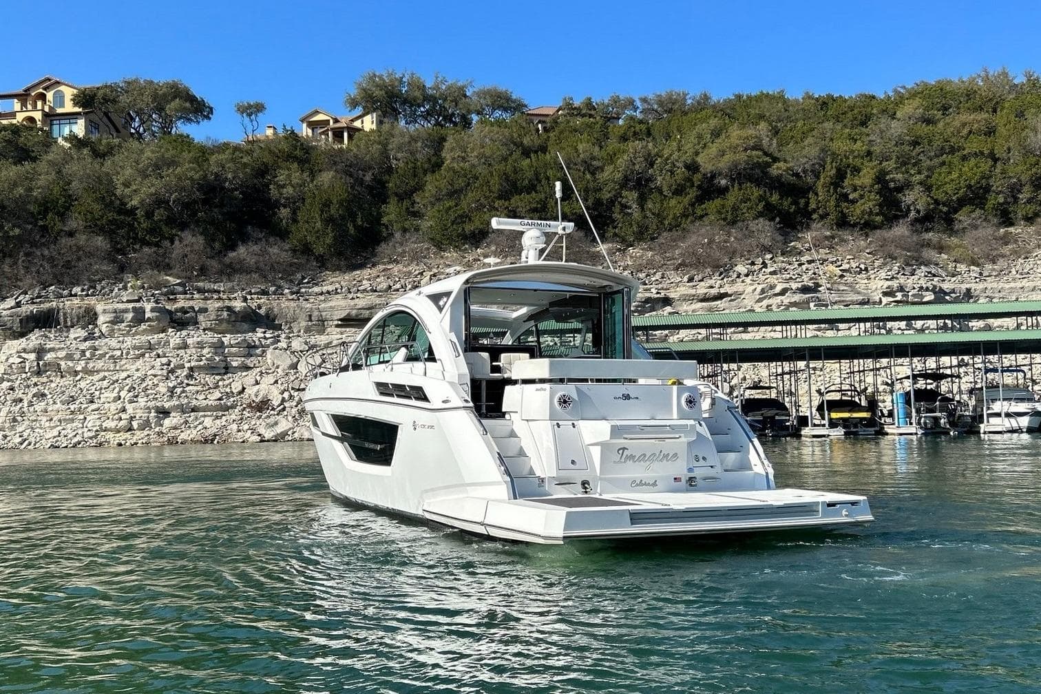 2021 Cruisers Yachts 50 Cantius on scenic lake with rocky shoreline backdrop.
