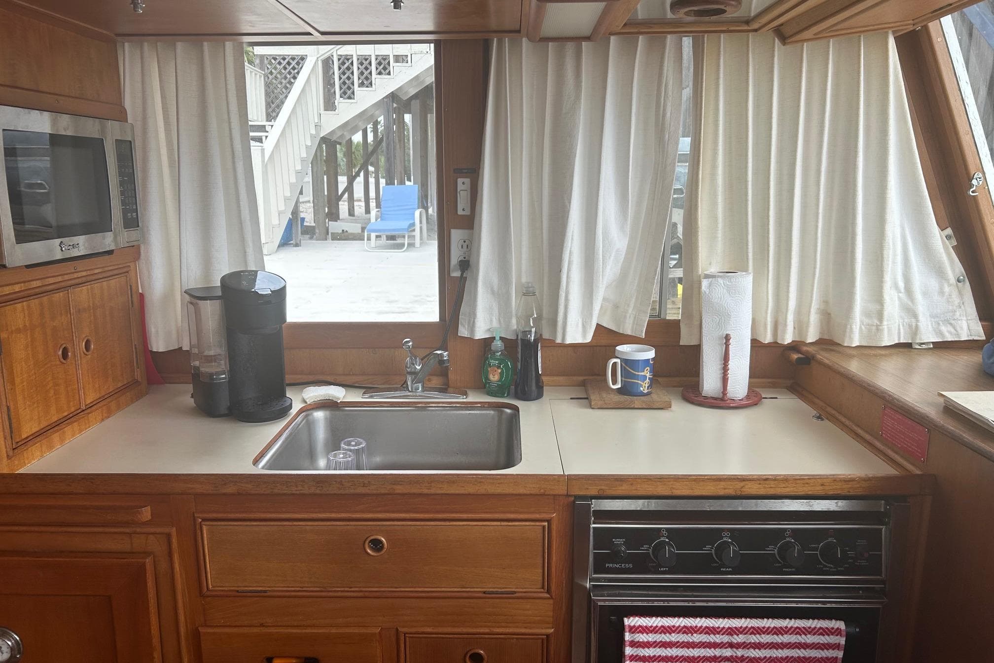 1996 Grand Banks 36 Motoryacht kitchen with sink, microwave, and stove, featuring wooden cabinetry.