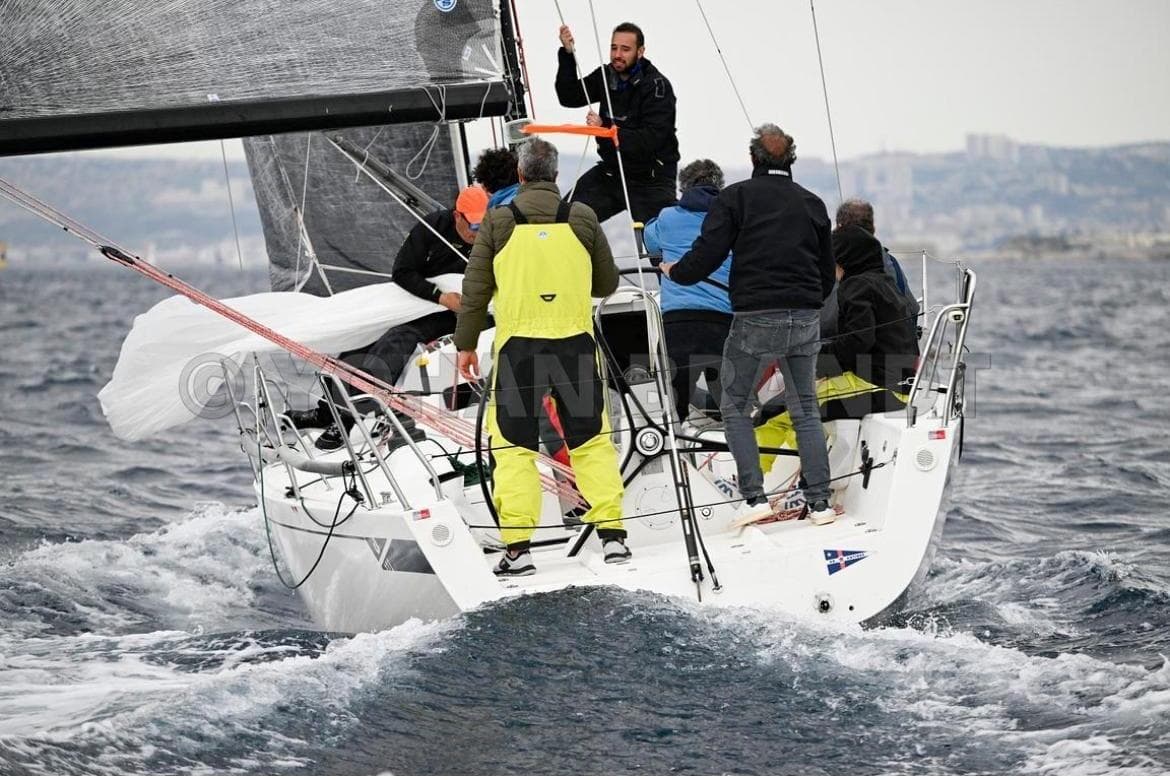 Sailors navigating a 2013 J Boats J/111 yacht in choppy waters.