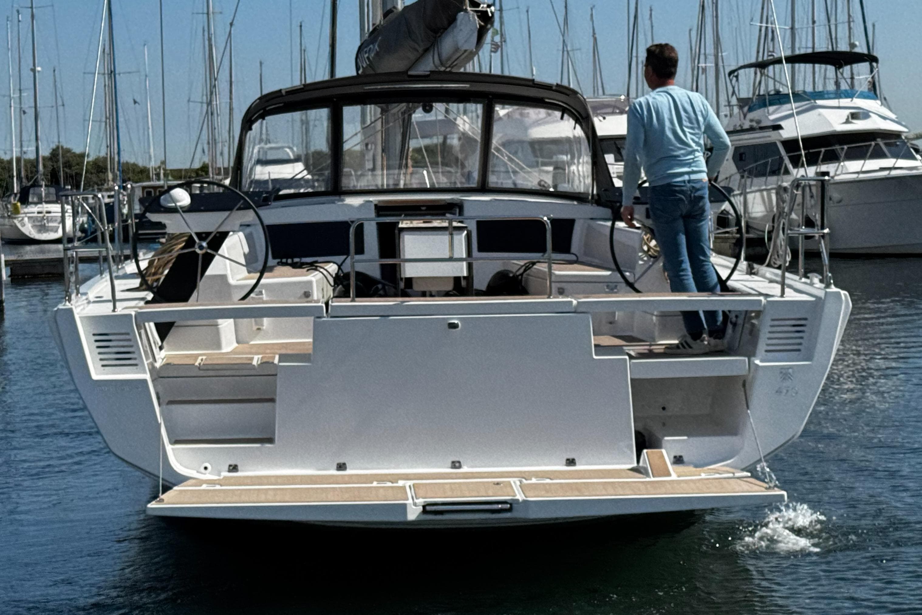 2024 Dufour 470 yacht in marina, rear view with person on deck.