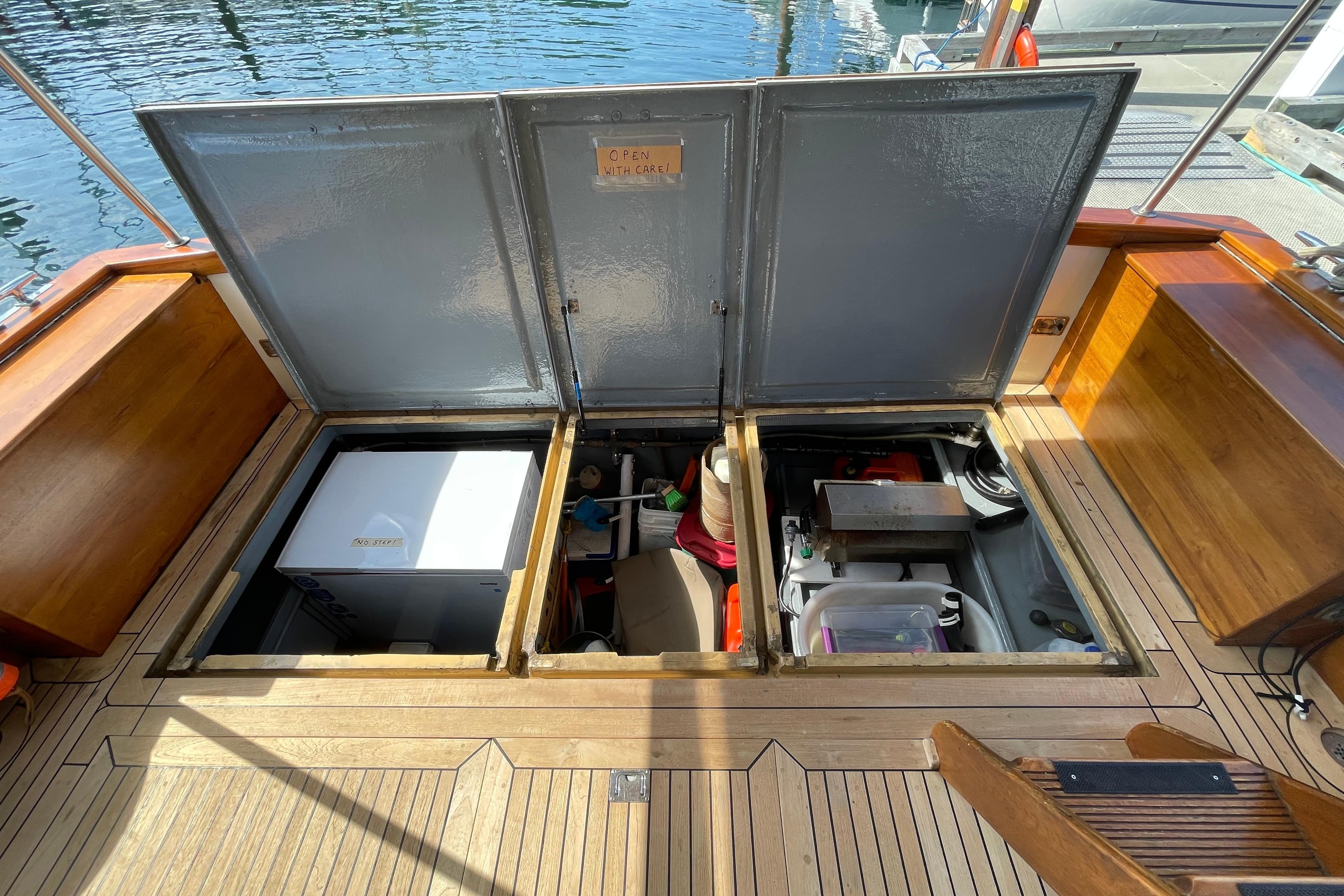 Open storage compartments on 1979 Canoe Cove 53 boat deck, revealing equipment and supplies.