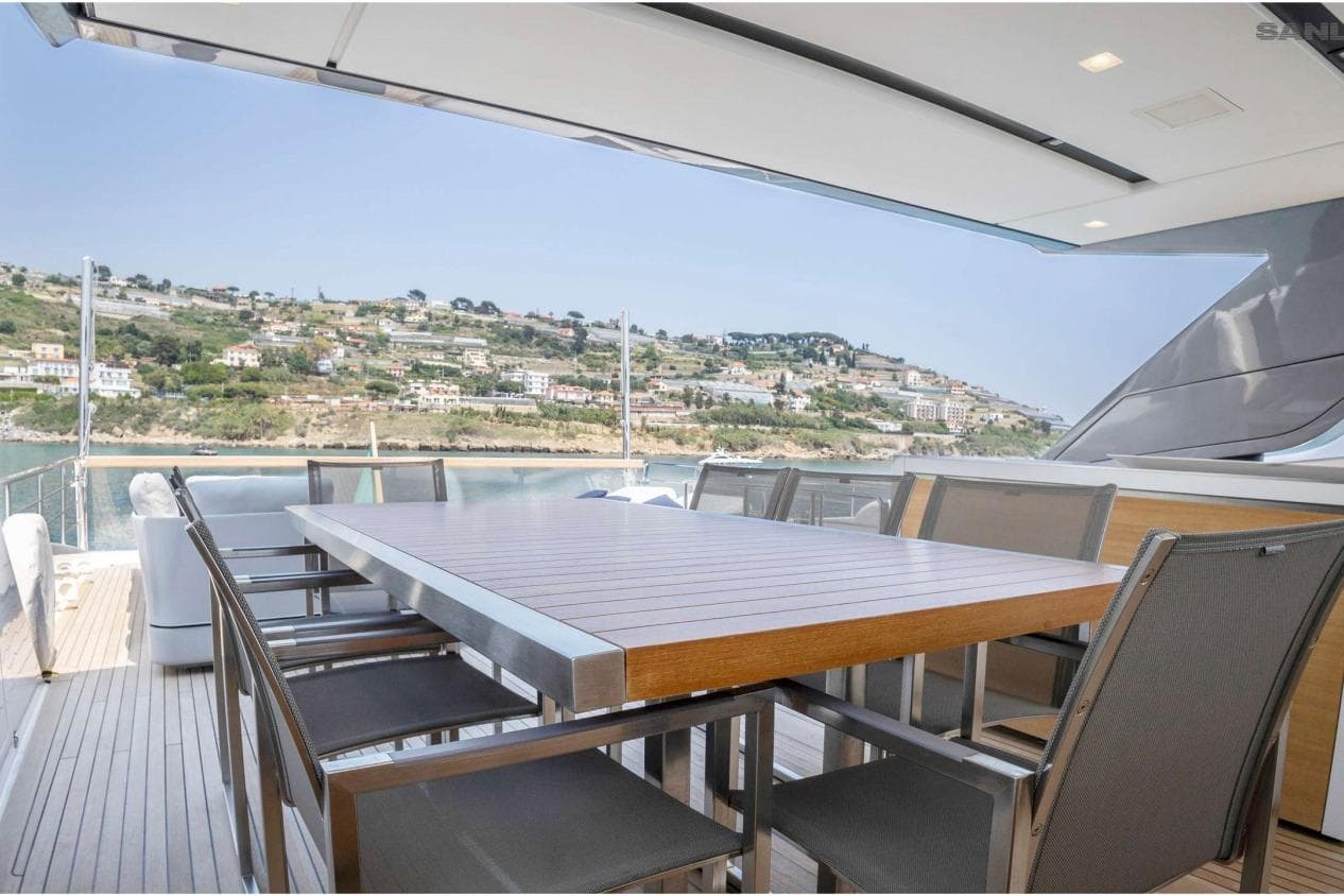 Outdoor dining area on 2016 Sanlorenzo SL96 yacht with scenic coastal view.