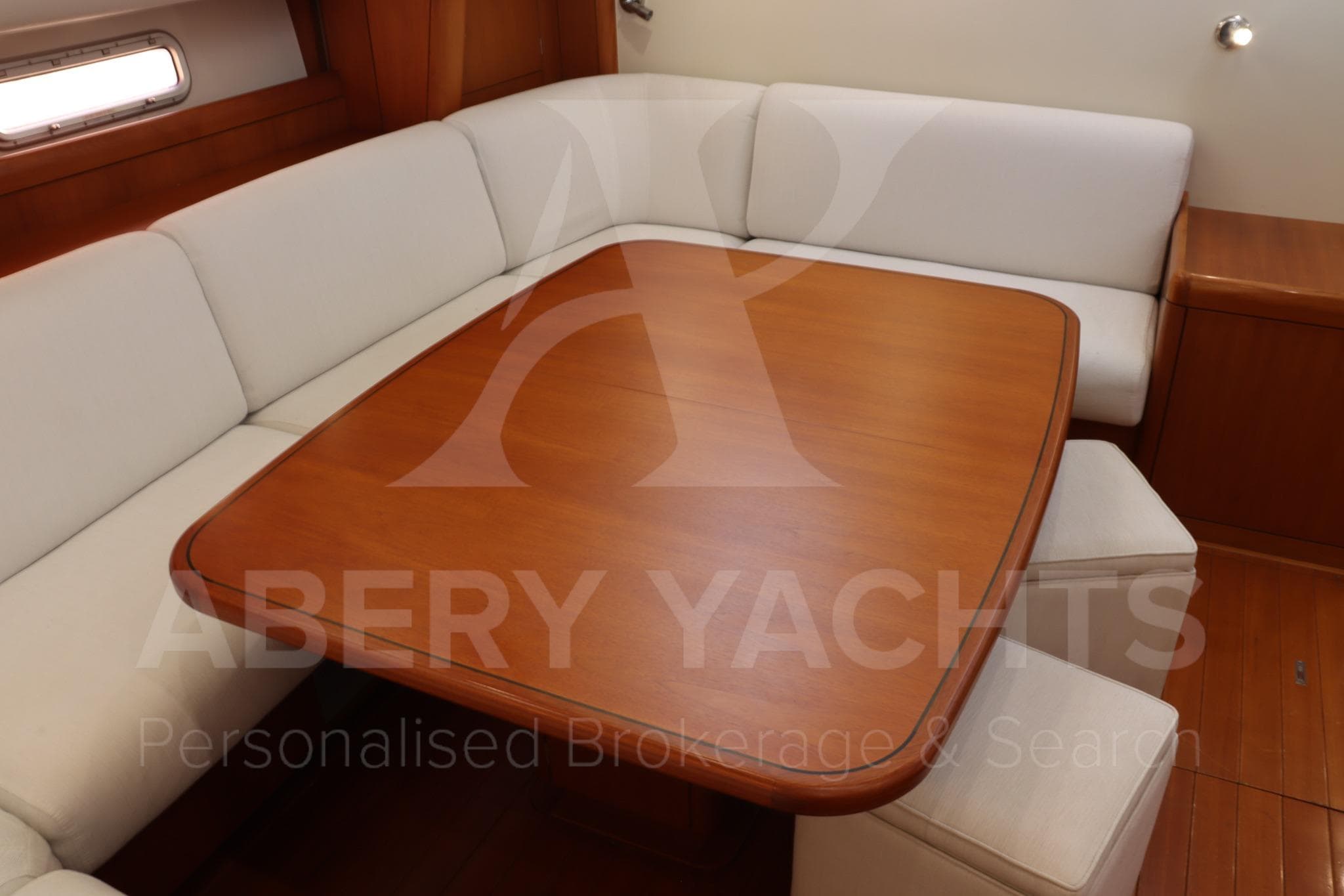Interior of 2008 Oyster 72 yacht with wooden table and white seating.