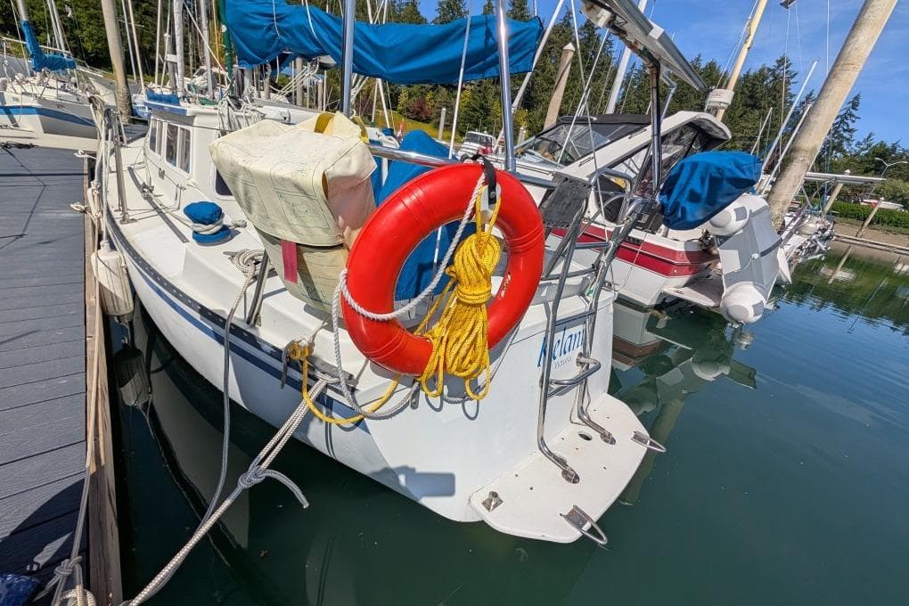 1986 Gulf Pilothouse sailboat docked, featuring a red lifebuoy and blue canopy.