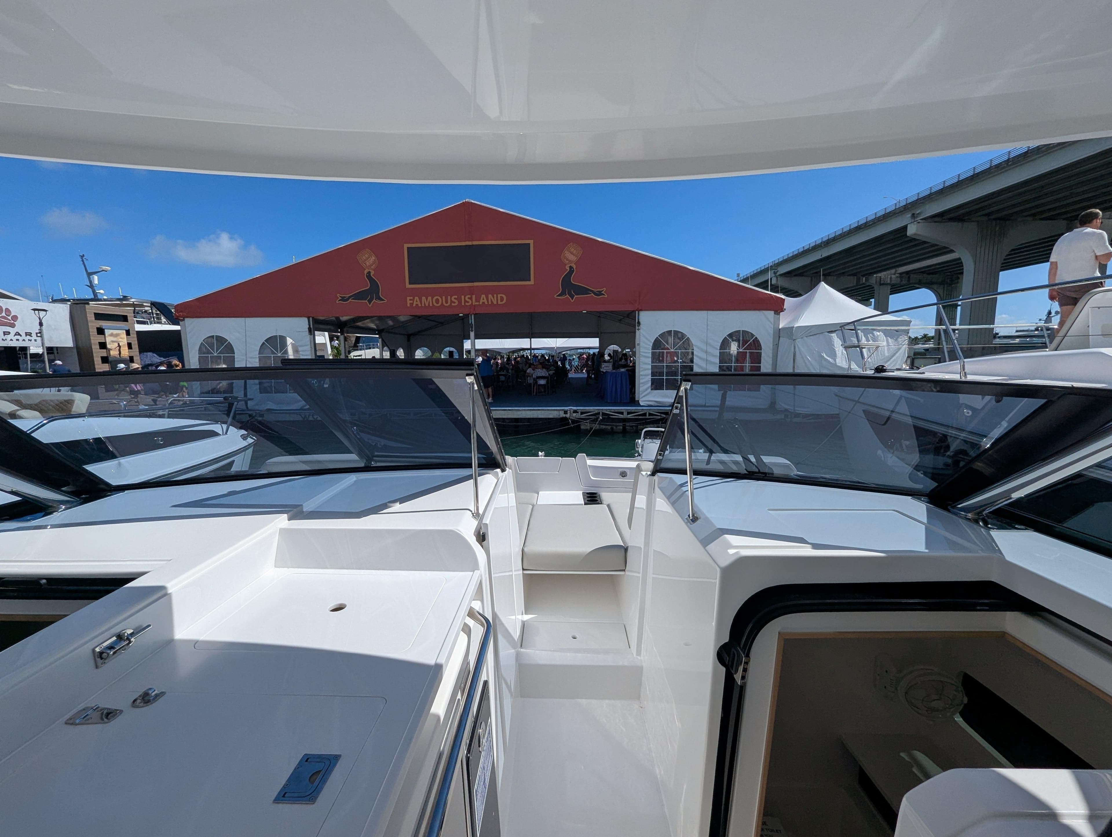 2025 Aquila 32 Sport yacht at a marina with a red tent and bridge in the background.