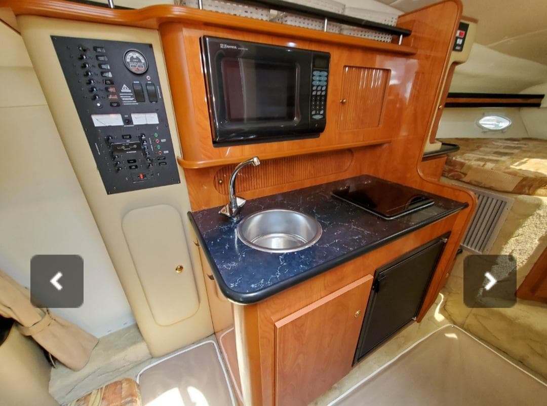 2004 Rinker Fiesta Vee 290 boat interior with kitchenette, microwave, sink, and control panel.