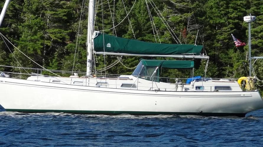 1978 Rival 41C sailboat with green sails on a forested lake.