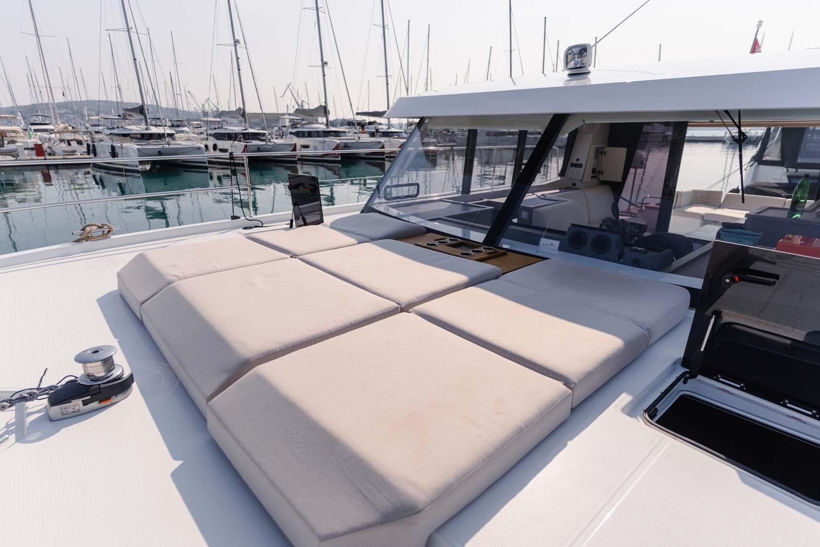 2022 Fountaine Pajot MY4.S yacht with spacious sunbathing area in marina setting.