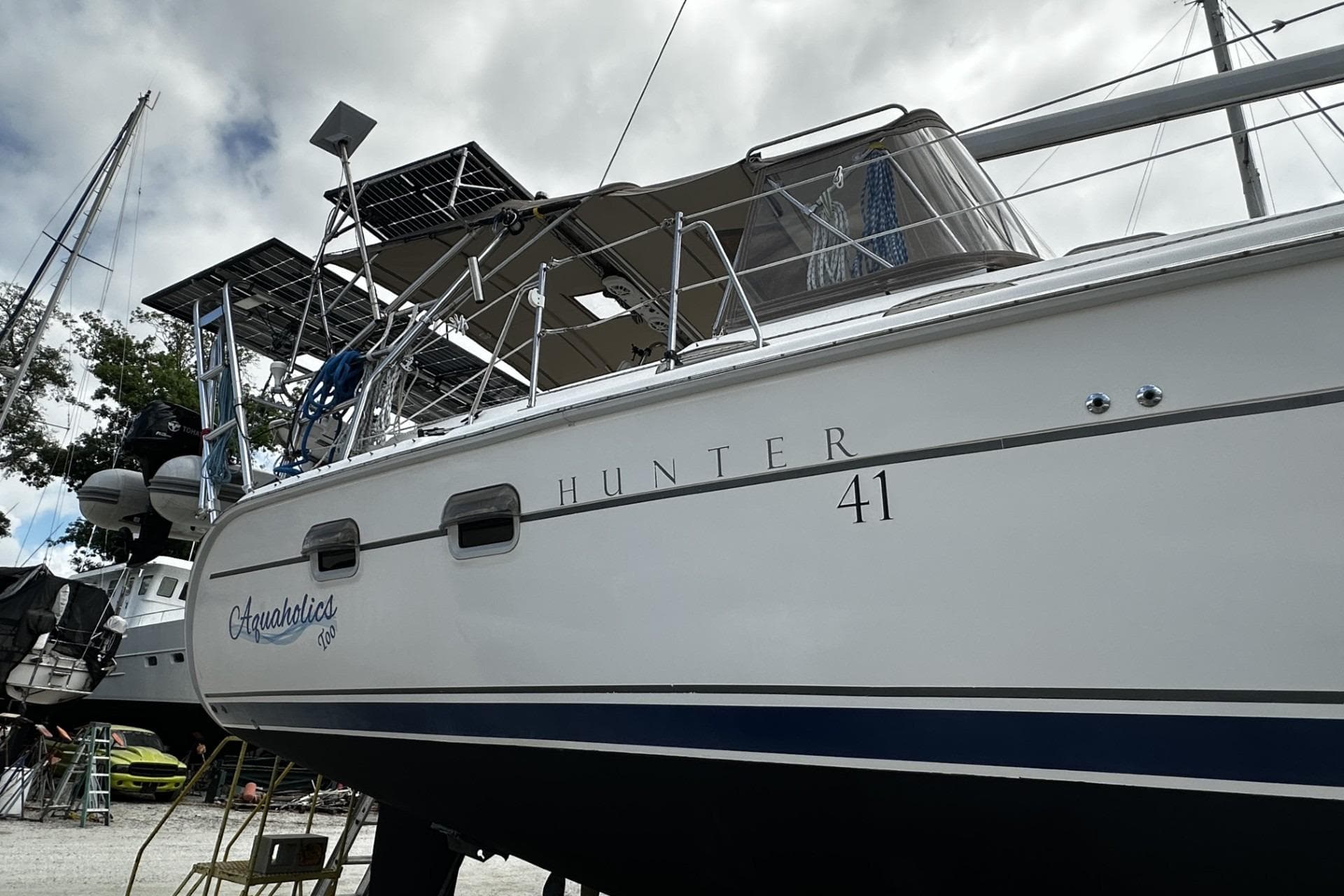 2004 Hunter 41 Aft Cockpit sailboat with solar panels, docked under cloudy skies.