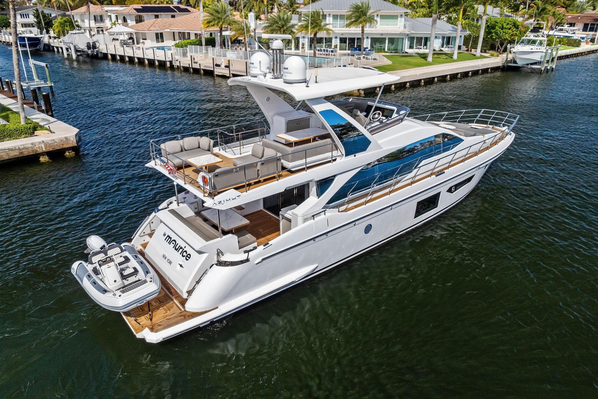 Luxurious 2020 Azimut 66 yacht cruising near waterfront homes.