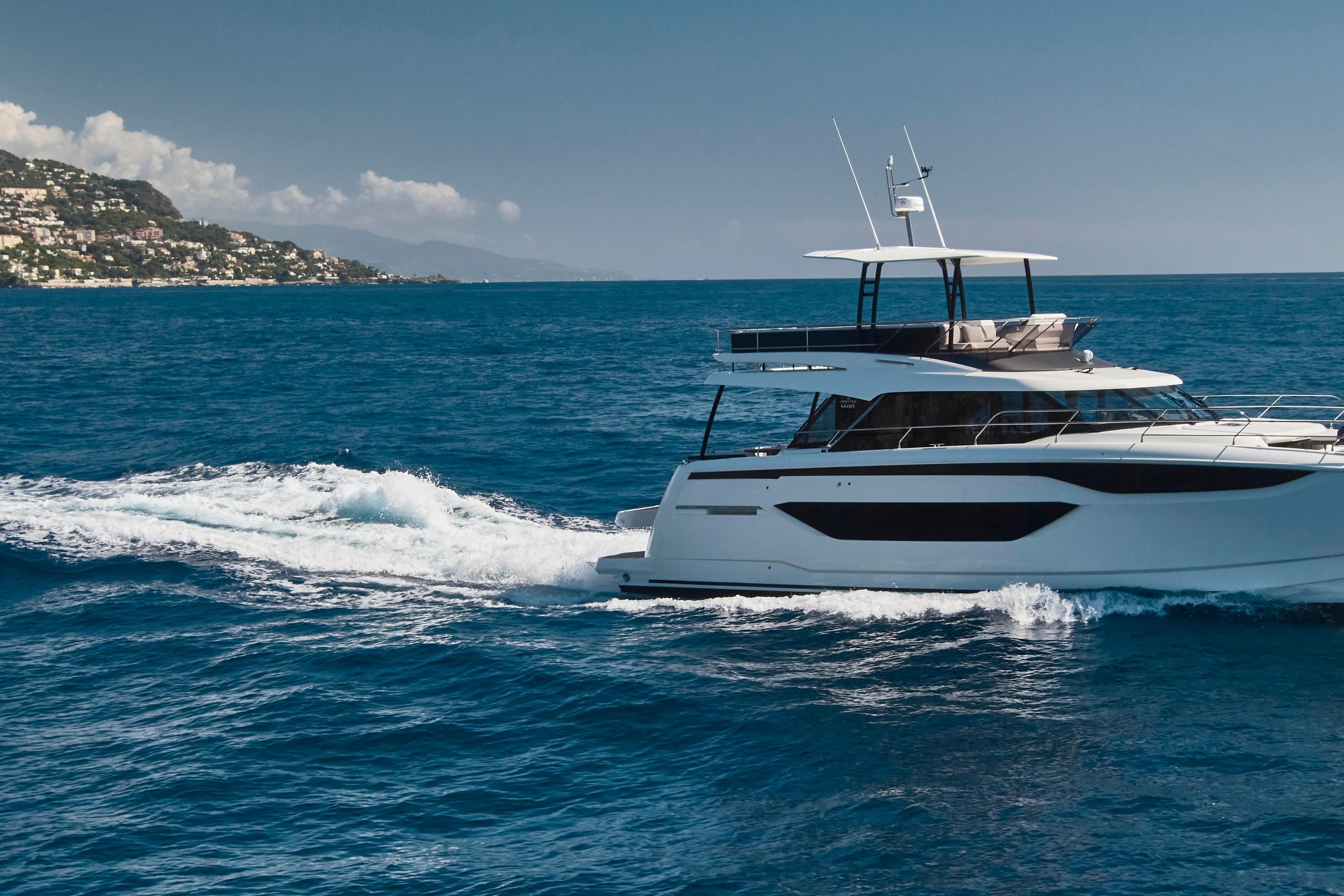 Luxurious 2025 Prestige M48 yacht cruising on open sea near scenic coastline.
