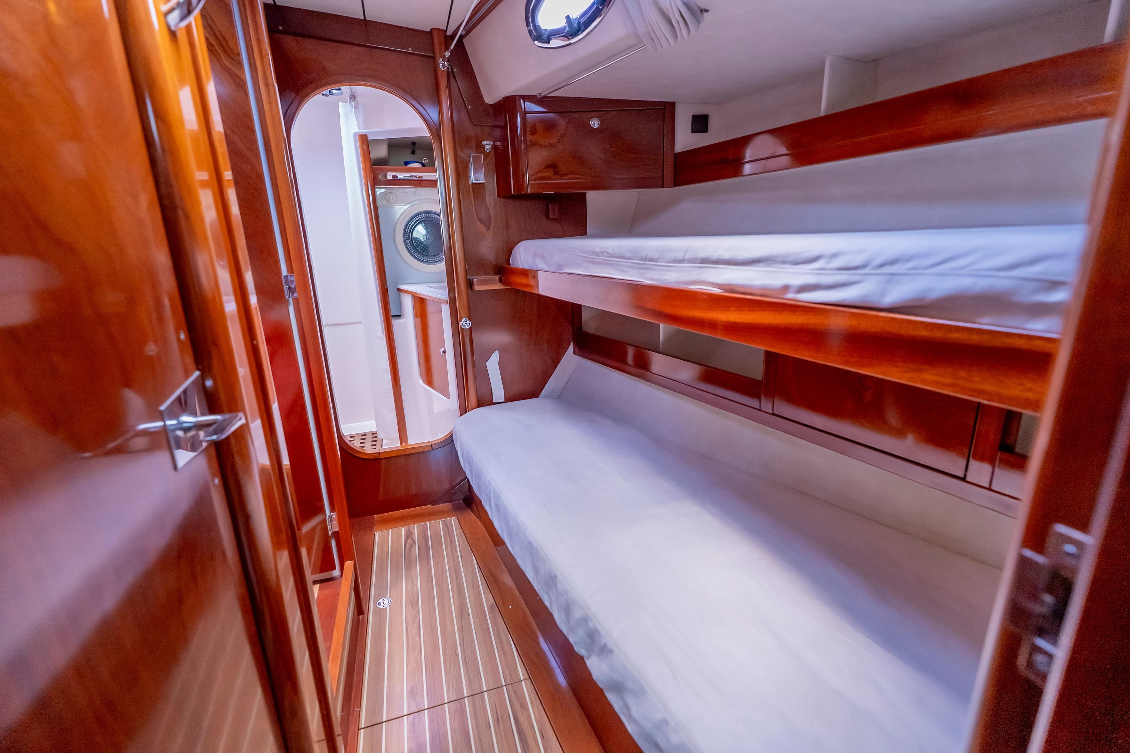 Luxurious cabin interior of 2010 Amel 54 yacht with wooden bunk beds and washer.