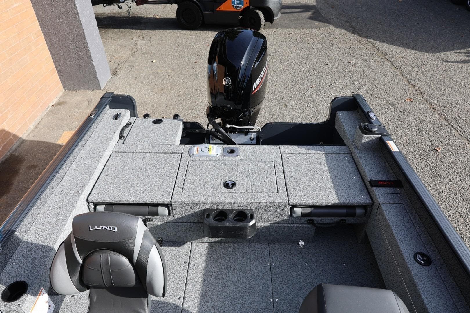 2026 Lund 1675 Adventure Sport boat interior with Mercury engine, gray seating, and storage compartments.
