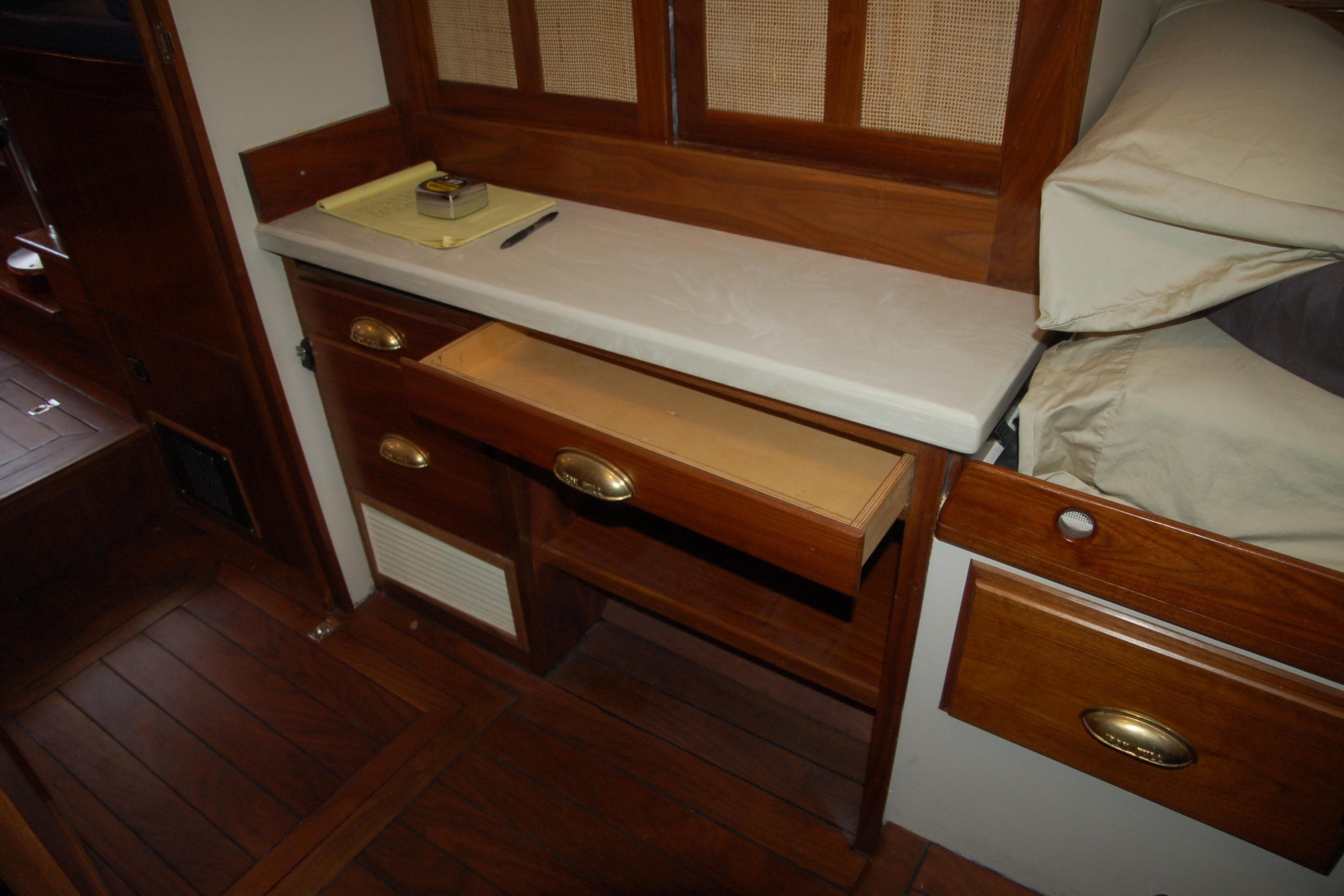 Wooden interior with open drawer, beige countertop, and bedding in a 2006 Custom Sprague model.