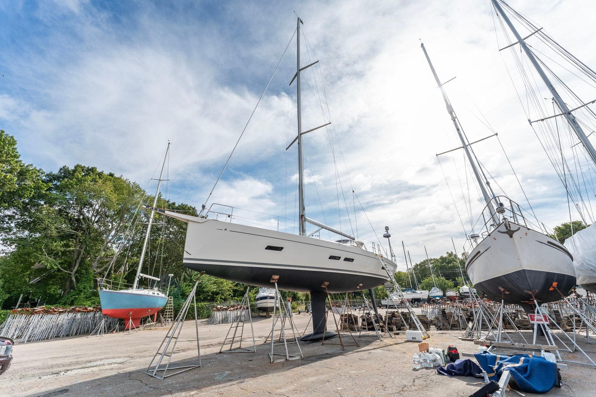 Italia Yachts 13.98, 2015 model, on dry dock with other sailboats under a cloudy sky.