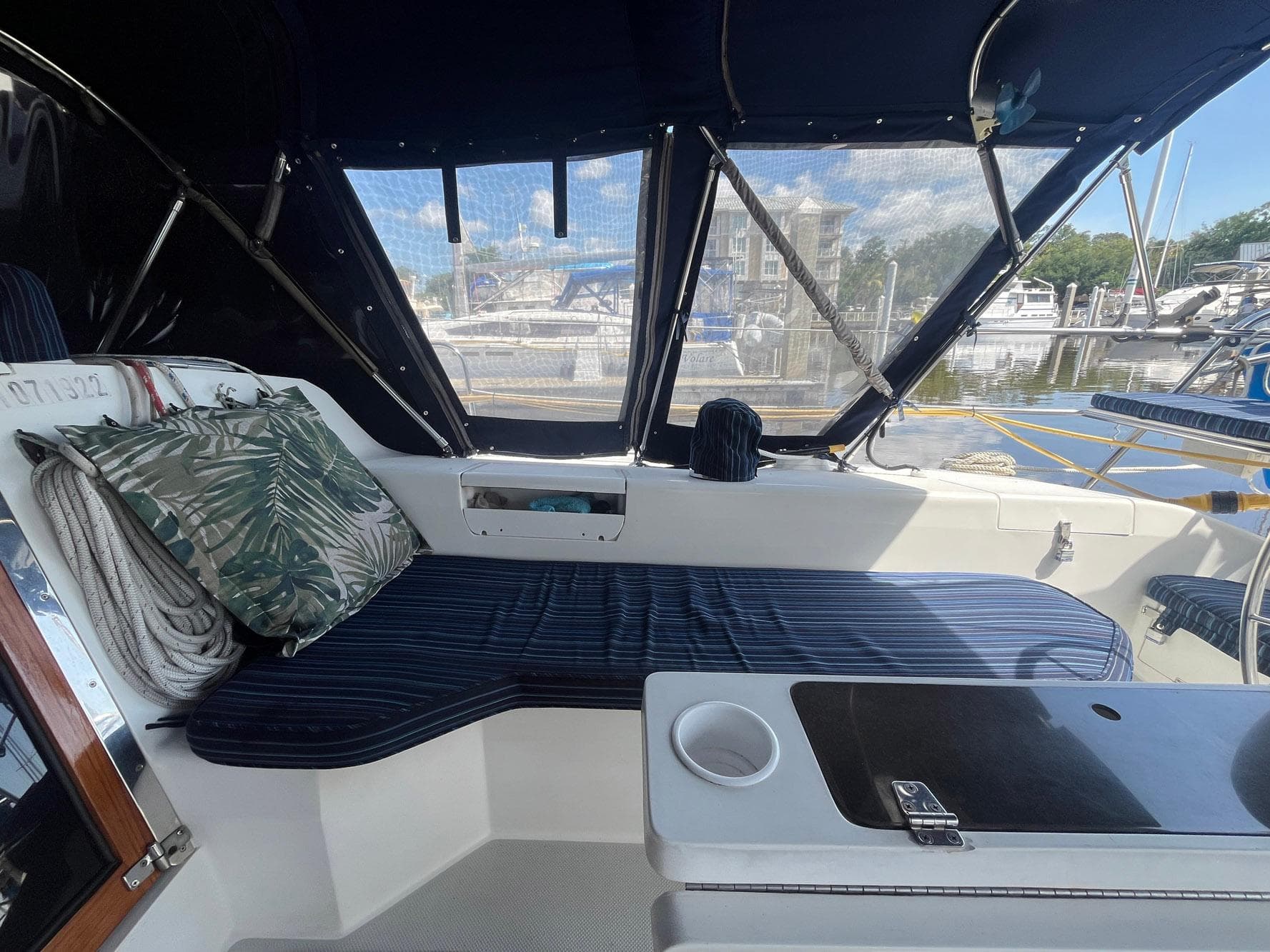 Cozy cockpit of 1999 Catalina 42 MkII sailboat with striped seating and tropical pillow.