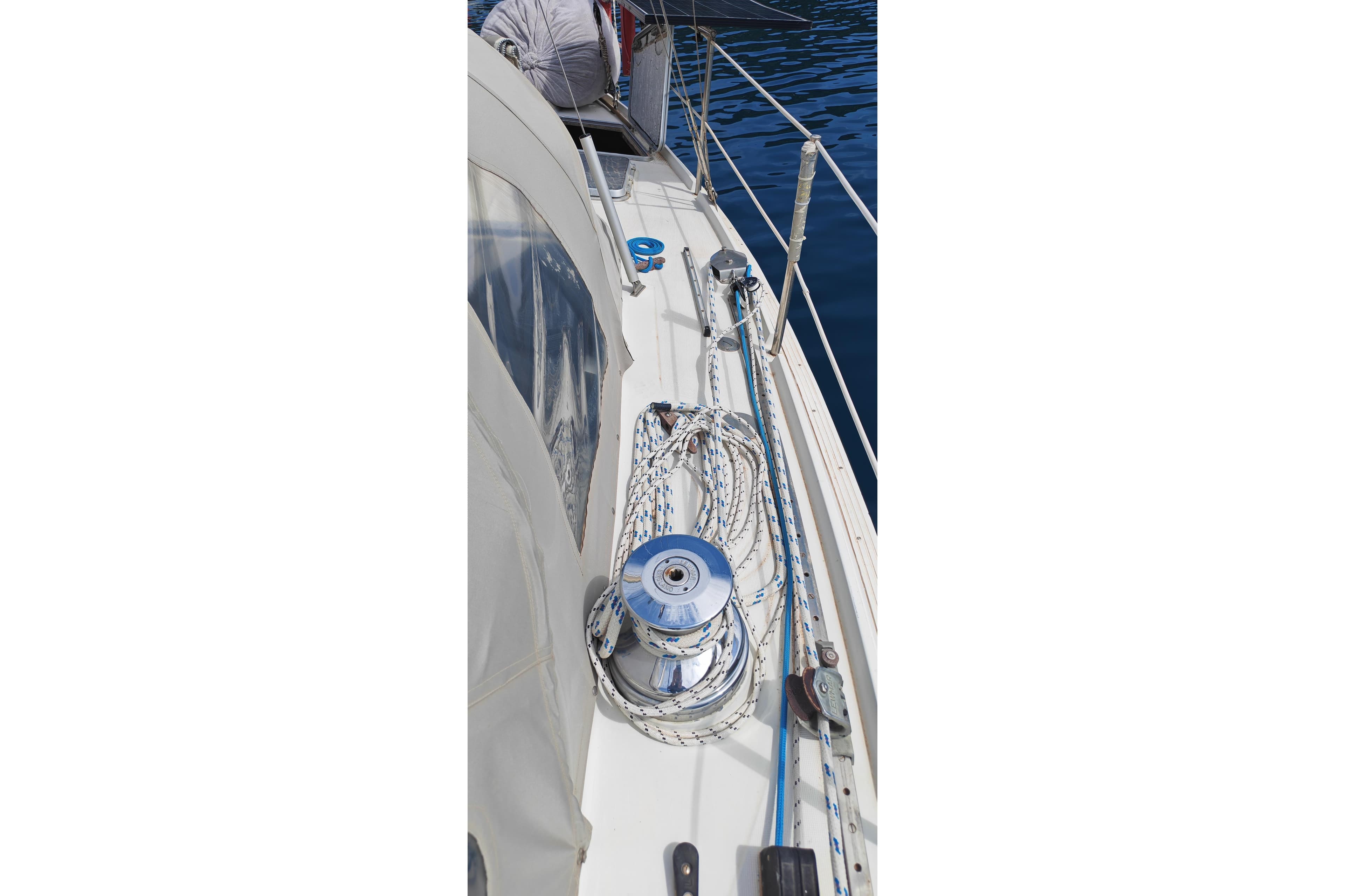 1972 Dufour Sortilege 41 sailboat deck with winch and ropes, docked on calm water.